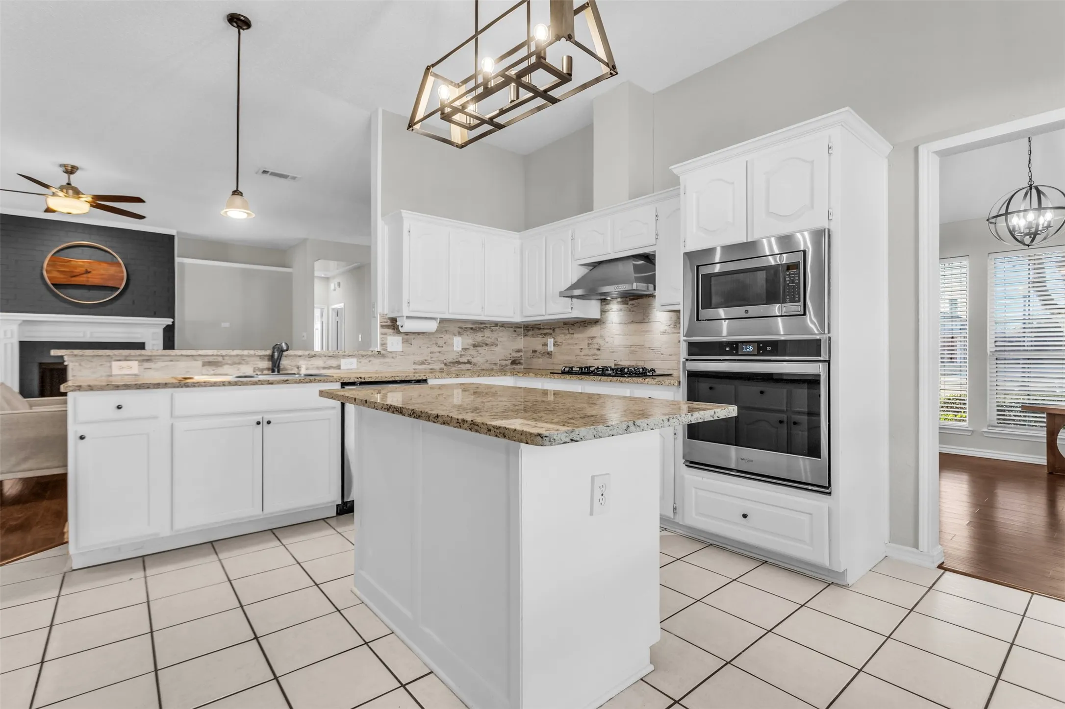 Modern kitchen space with built-in appliances, pendant lighting, and crisp white shaker cabinetry.