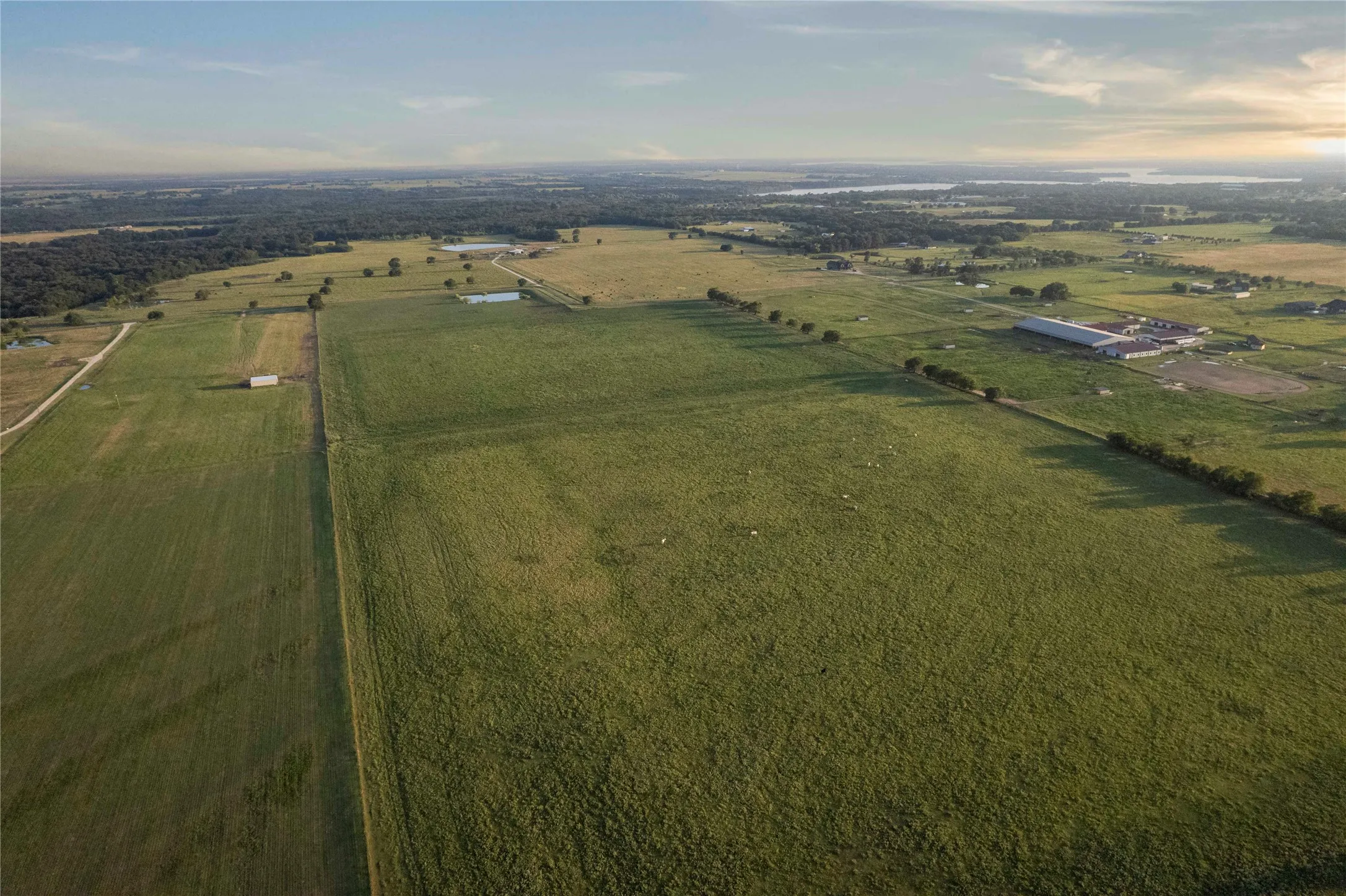 Aerial view of property and surrounding area featuring rural landscape and rows of crops
