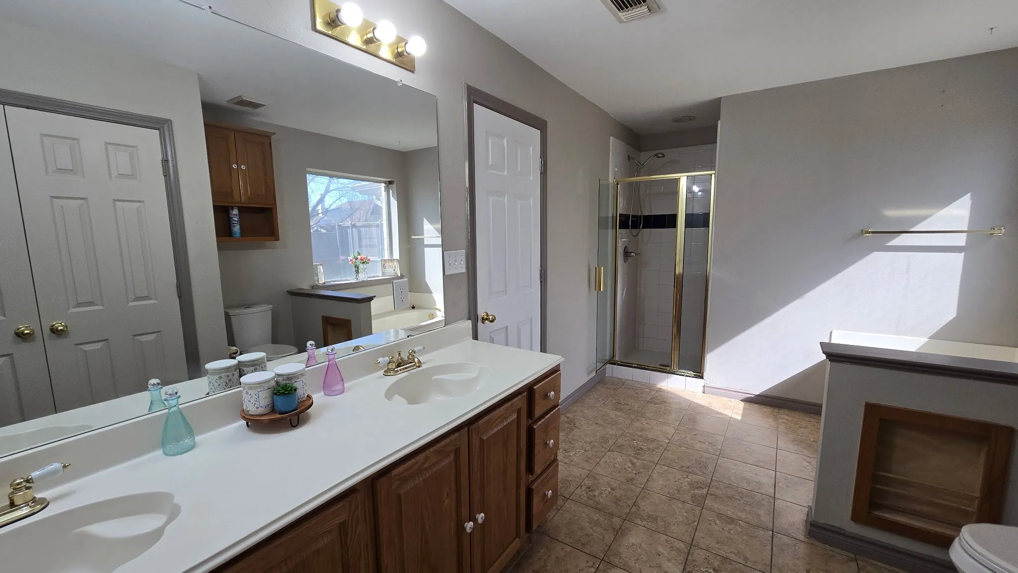 Full bath with double vanity, a shower stall, a garden tub, a closet, and dark tile patterned floors