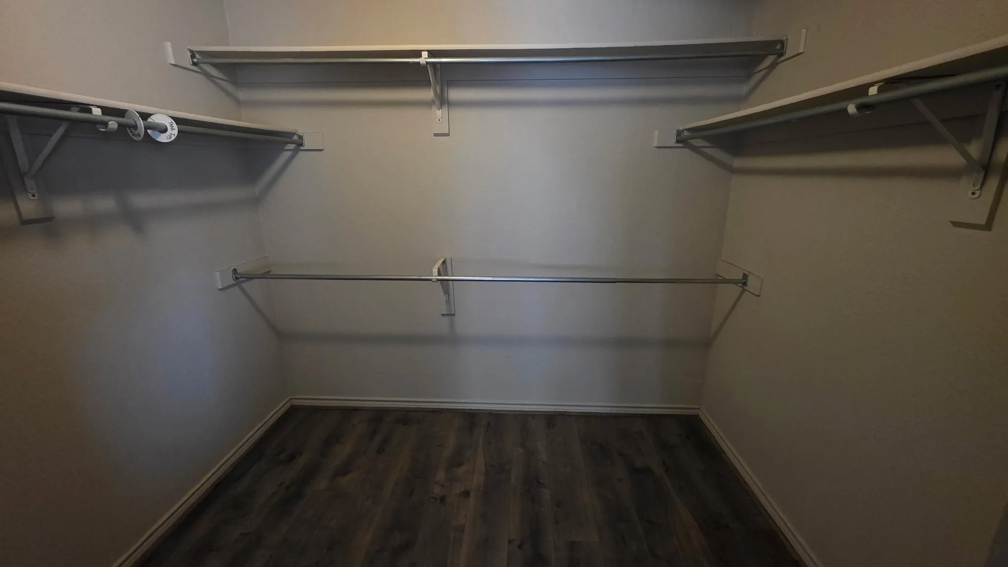 Walk in closet with dark wood finished floors