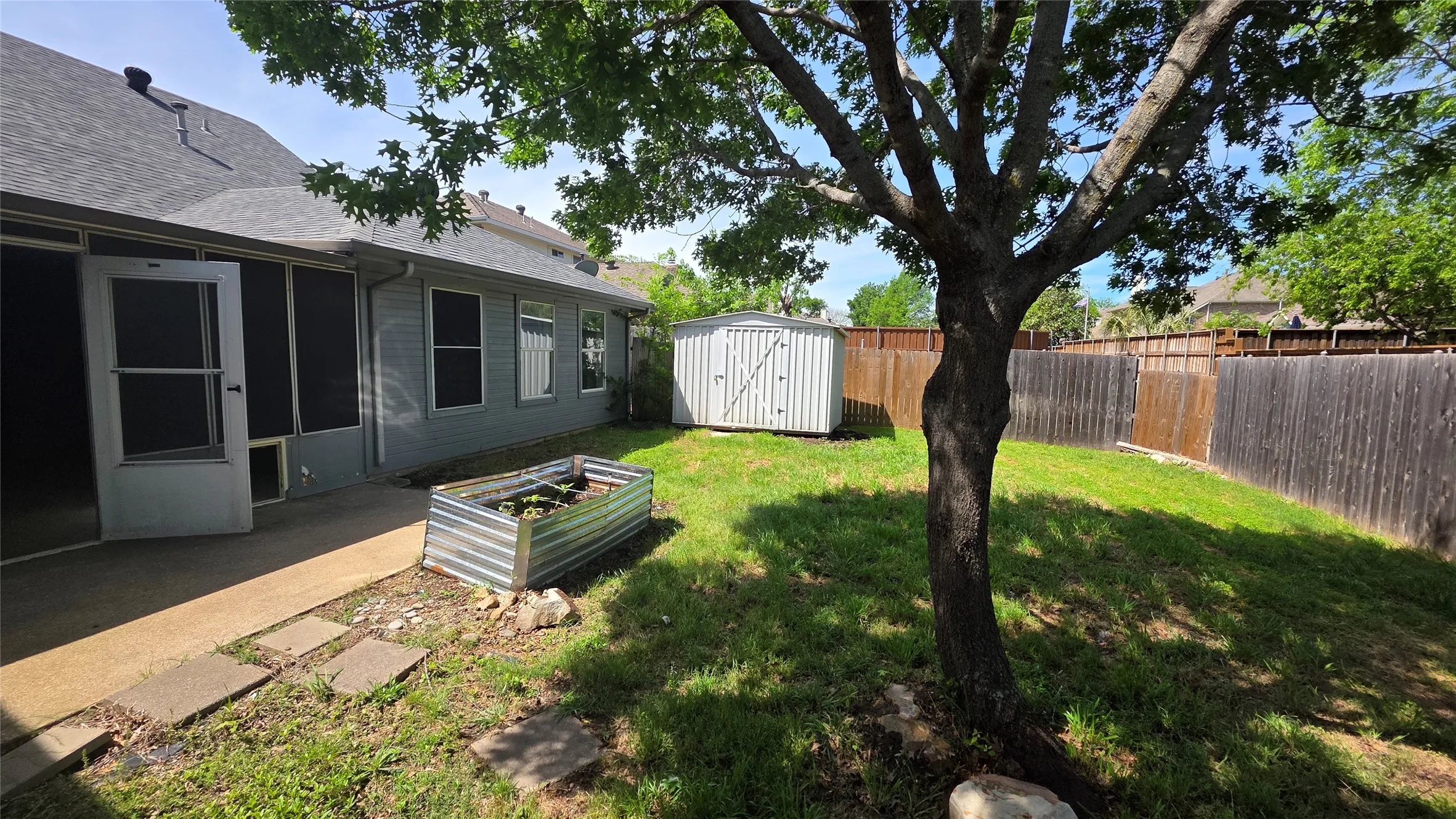 Fenced backyard featuring a shed and a vegetable garden