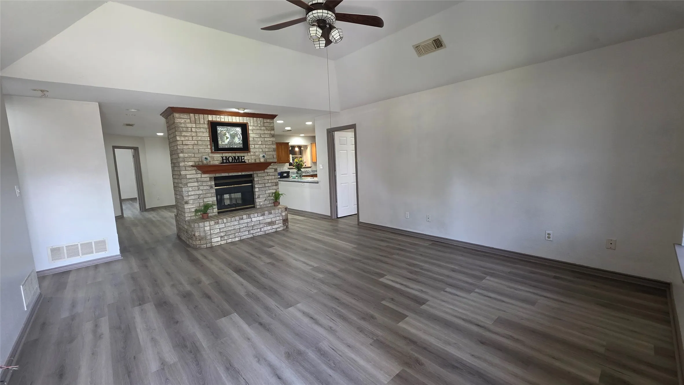 Unfurnished living room with ceiling fan, a fireplace, dark wood finished floors, and vaulted ceiling