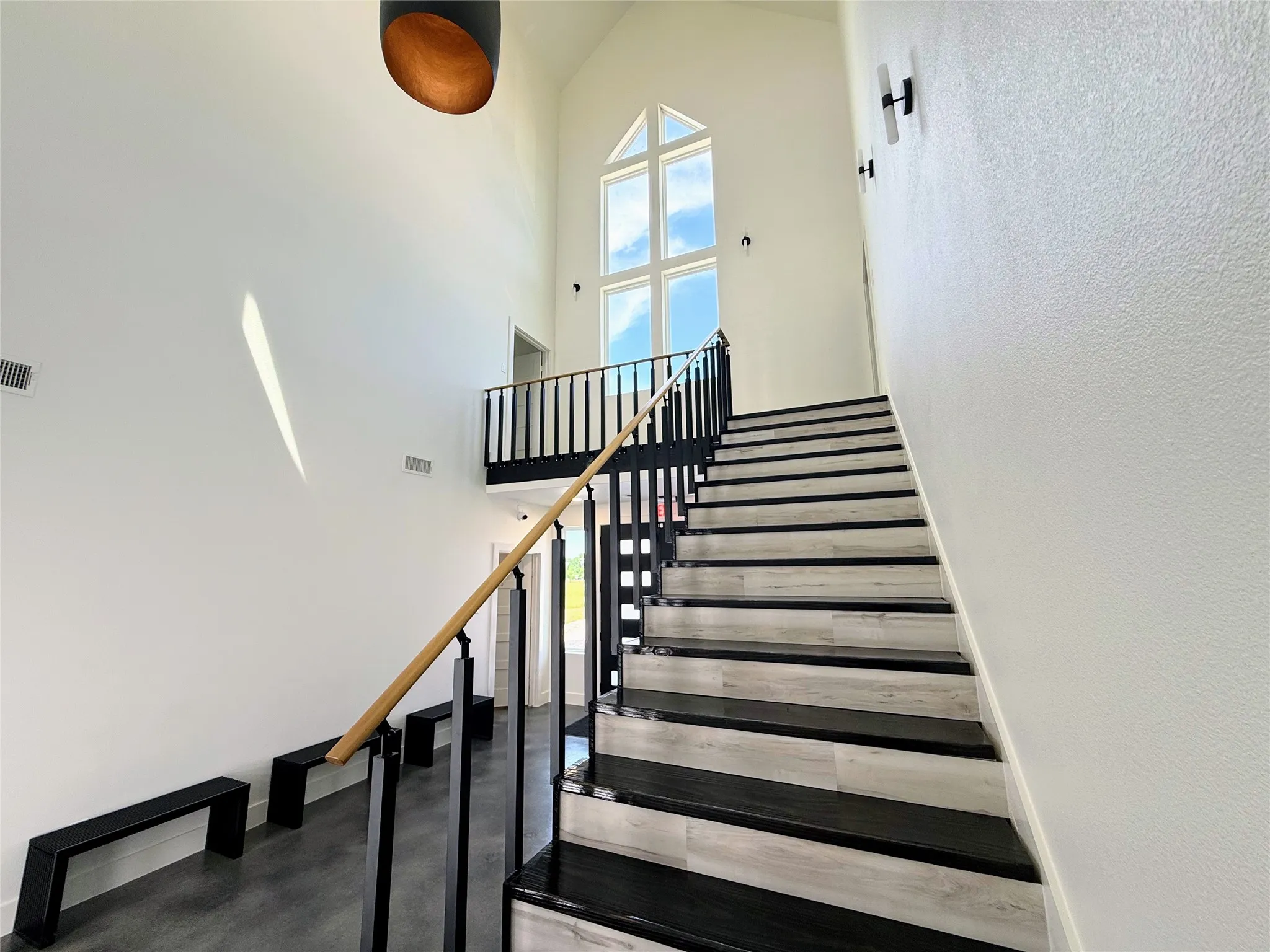 Staircase featuring a high ceiling and concrete flooring