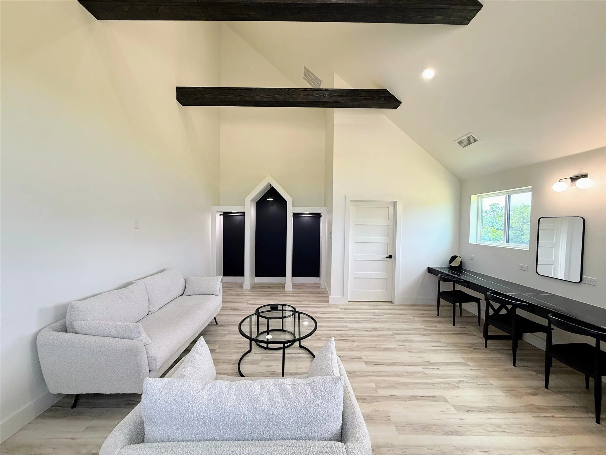 Living area featuring light wood-style flooring, high vaulted ceiling, and beamed ceiling
