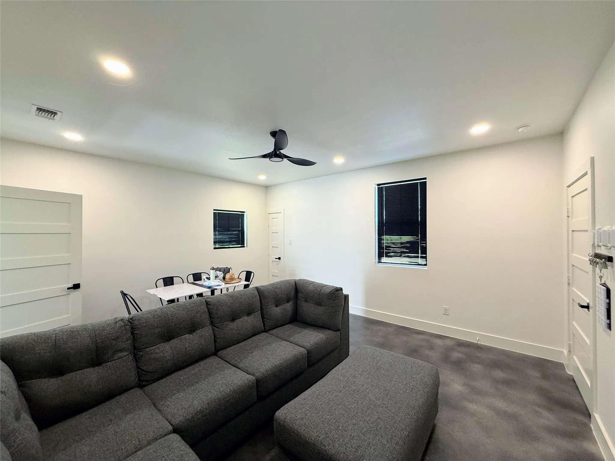 Living room with a ceiling fan, recessed lighting, and dark colored carpet