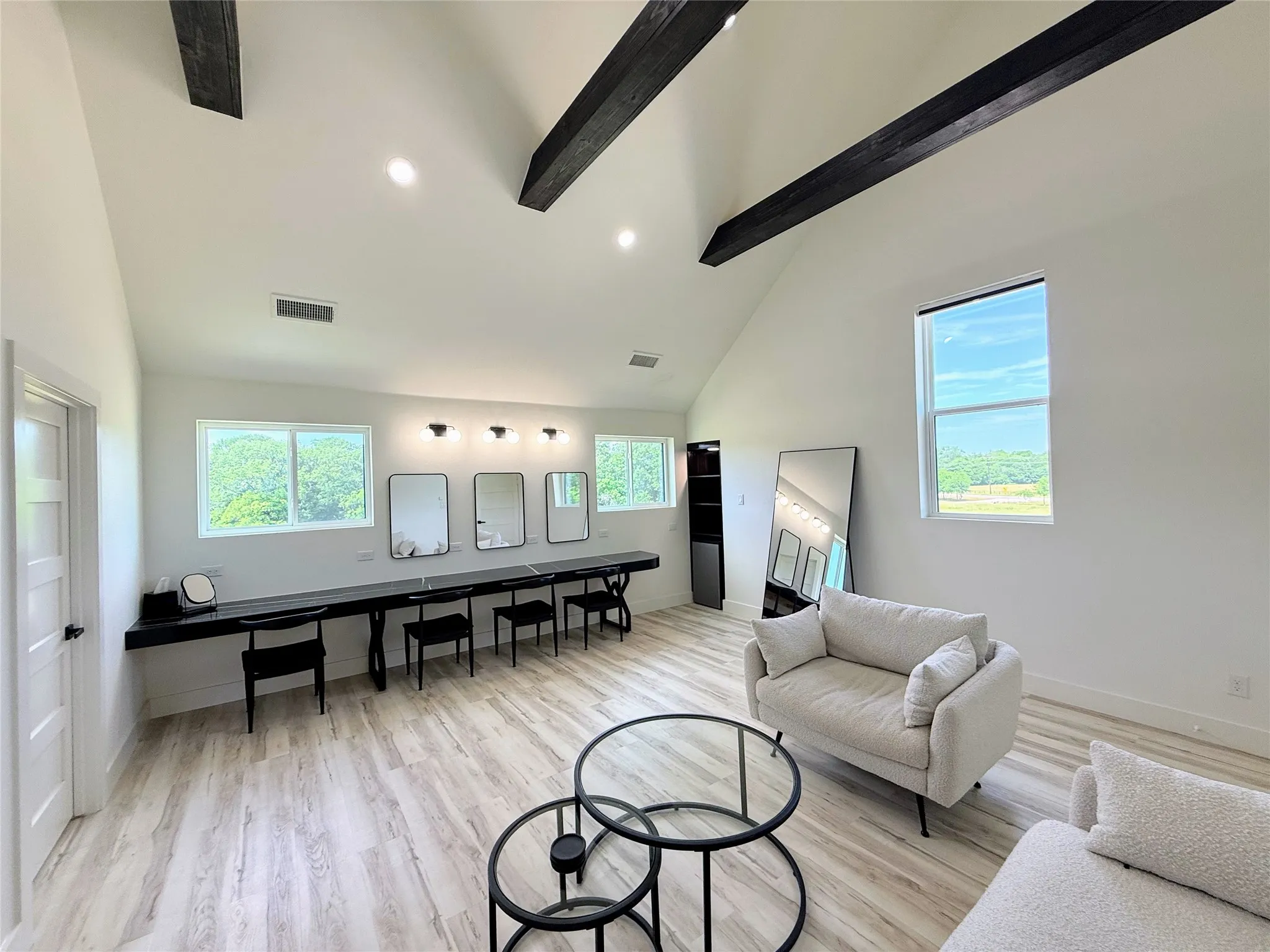 Living room featuring beamed ceiling, light wood-type flooring, high vaulted ceiling, and healthy amount of natural light