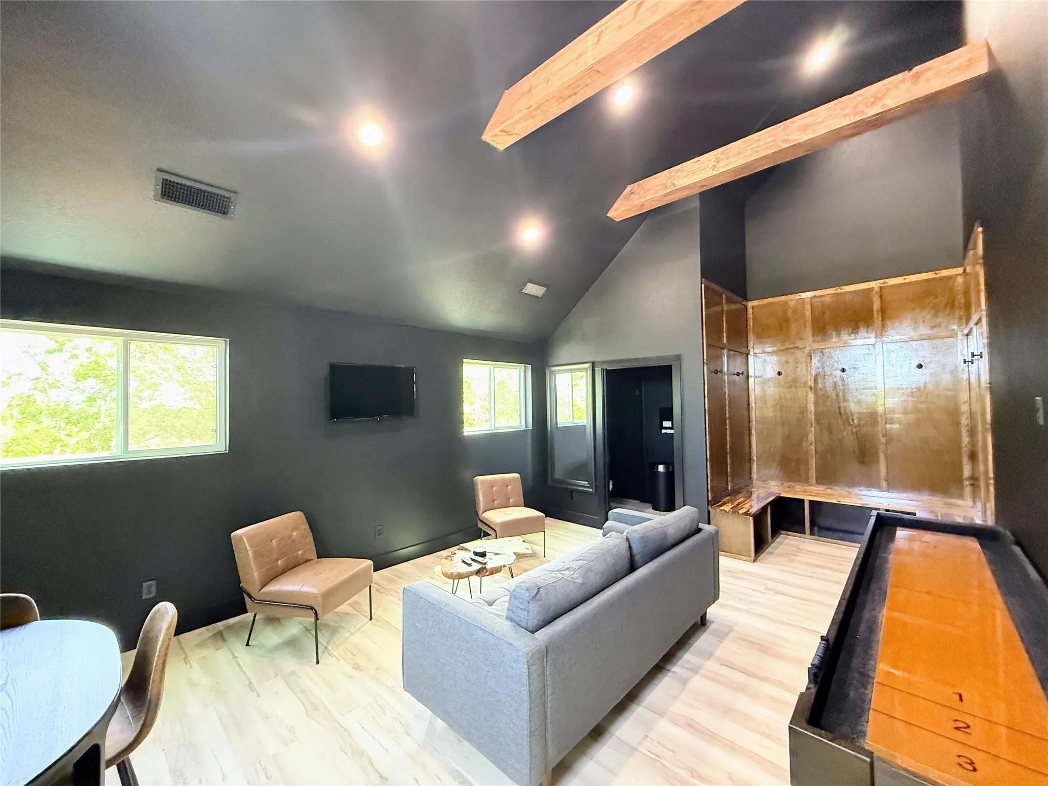 Living room with high vaulted ceiling, light wood-type flooring, and beamed ceiling
