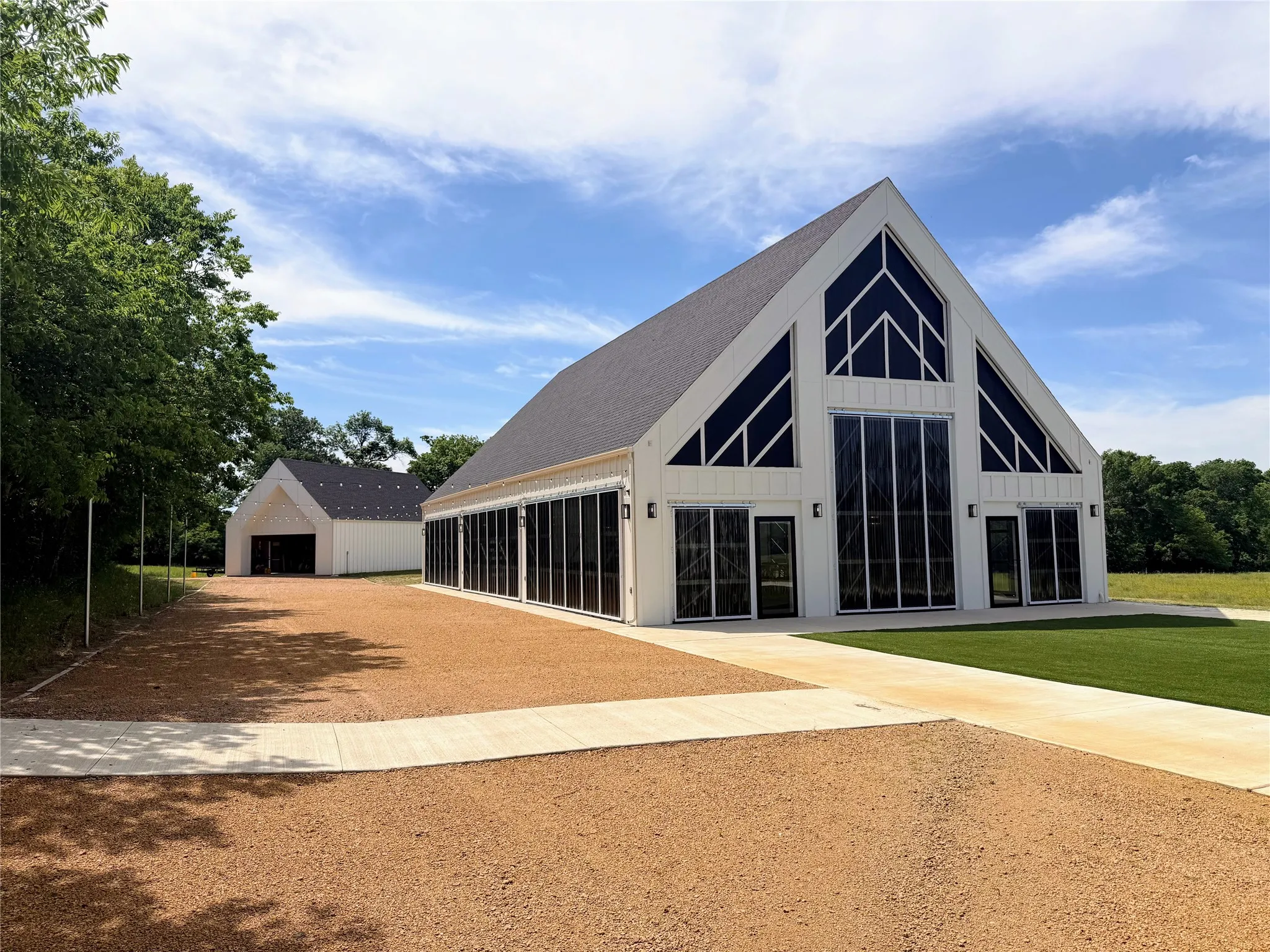 Back of property with board and batten siding, an outdoor structure, a detached garage, and dirt driveway