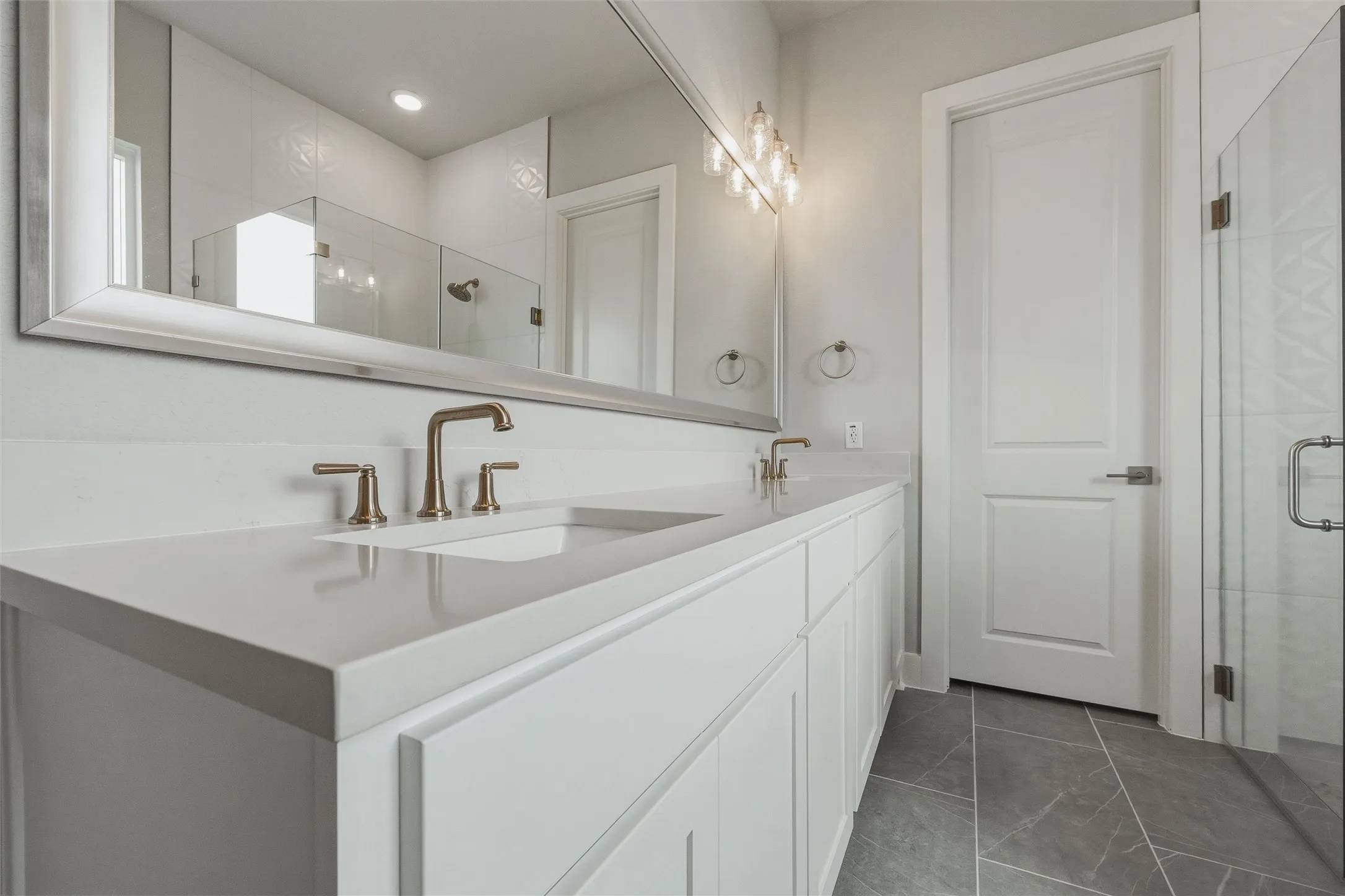 Dual vanity with light-toned countertop, under-mount sinks, and bronze-finish fixtures