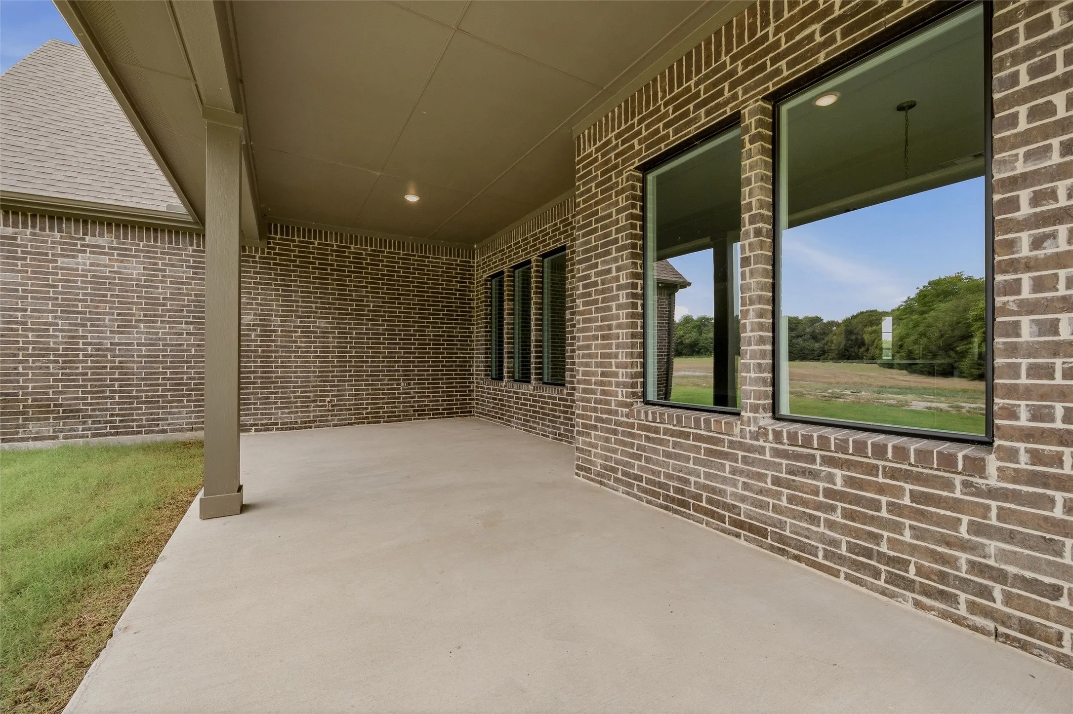Covered patio featuring a concrete surface and brick exterior