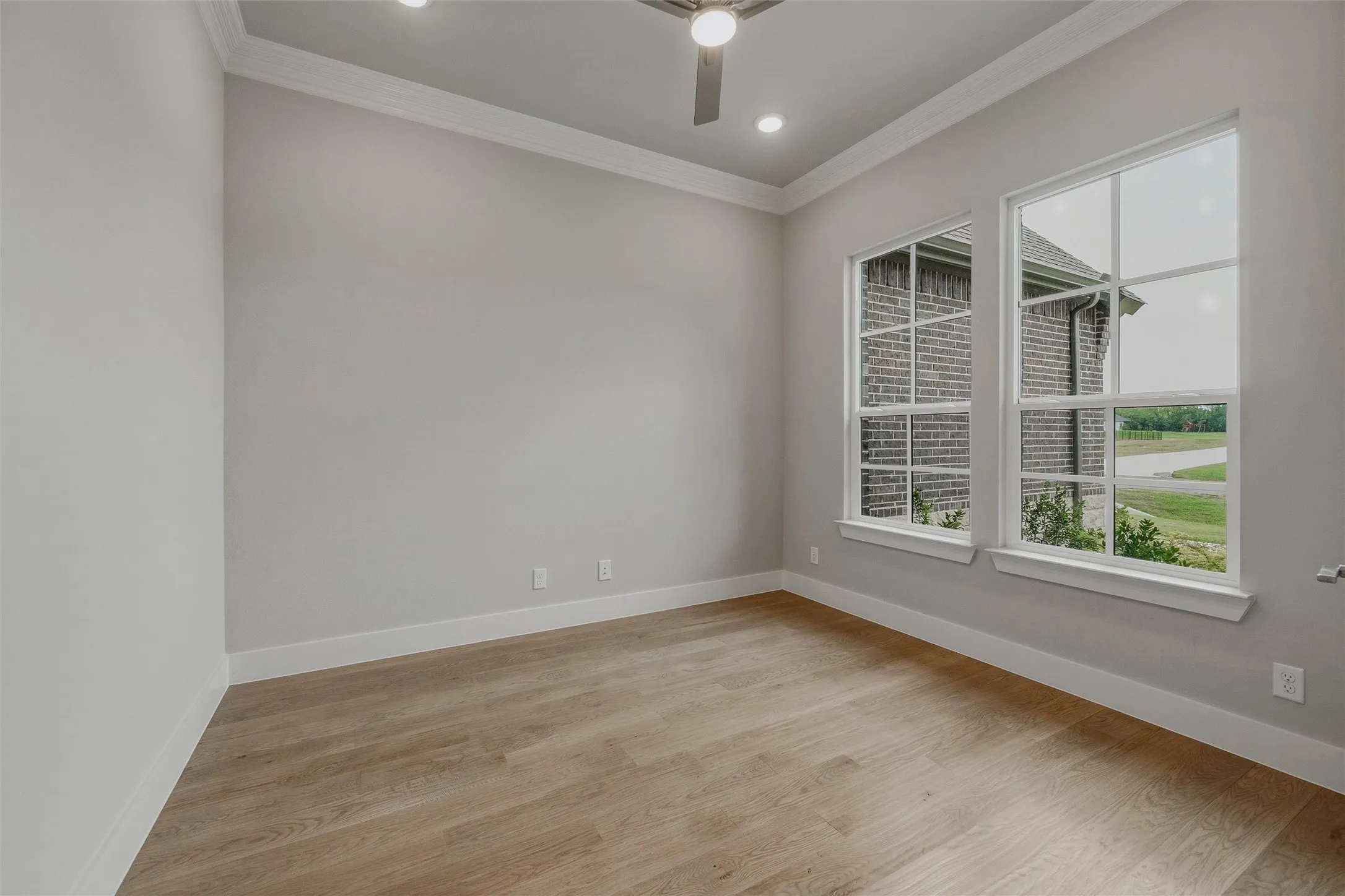 Wood-finish flooring, two large windows with white trim, recessed lighting, and a ceiling fan