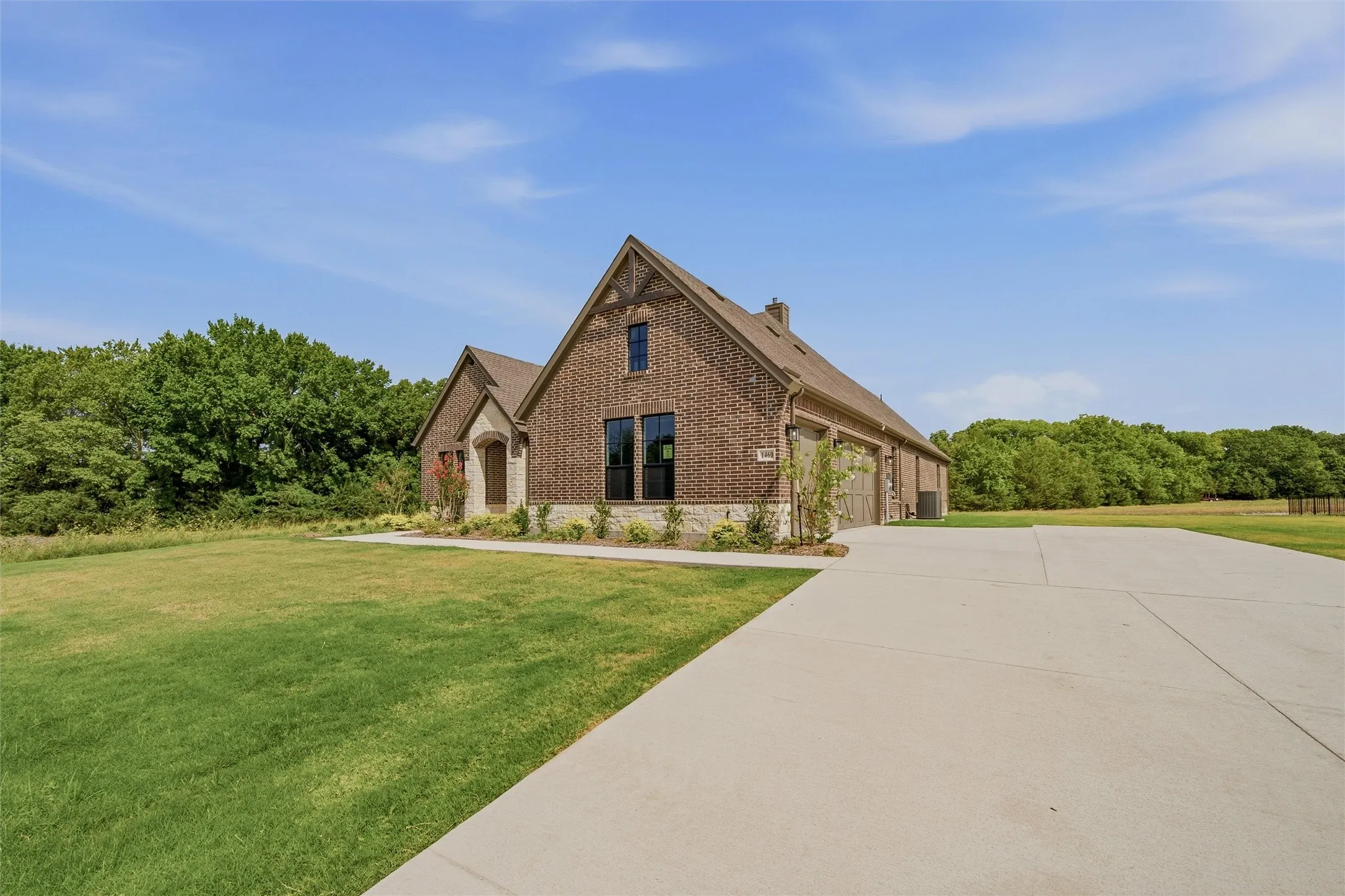 Brick and stone exterior featuring multiple gables, a concrete driveway, and an attached garage