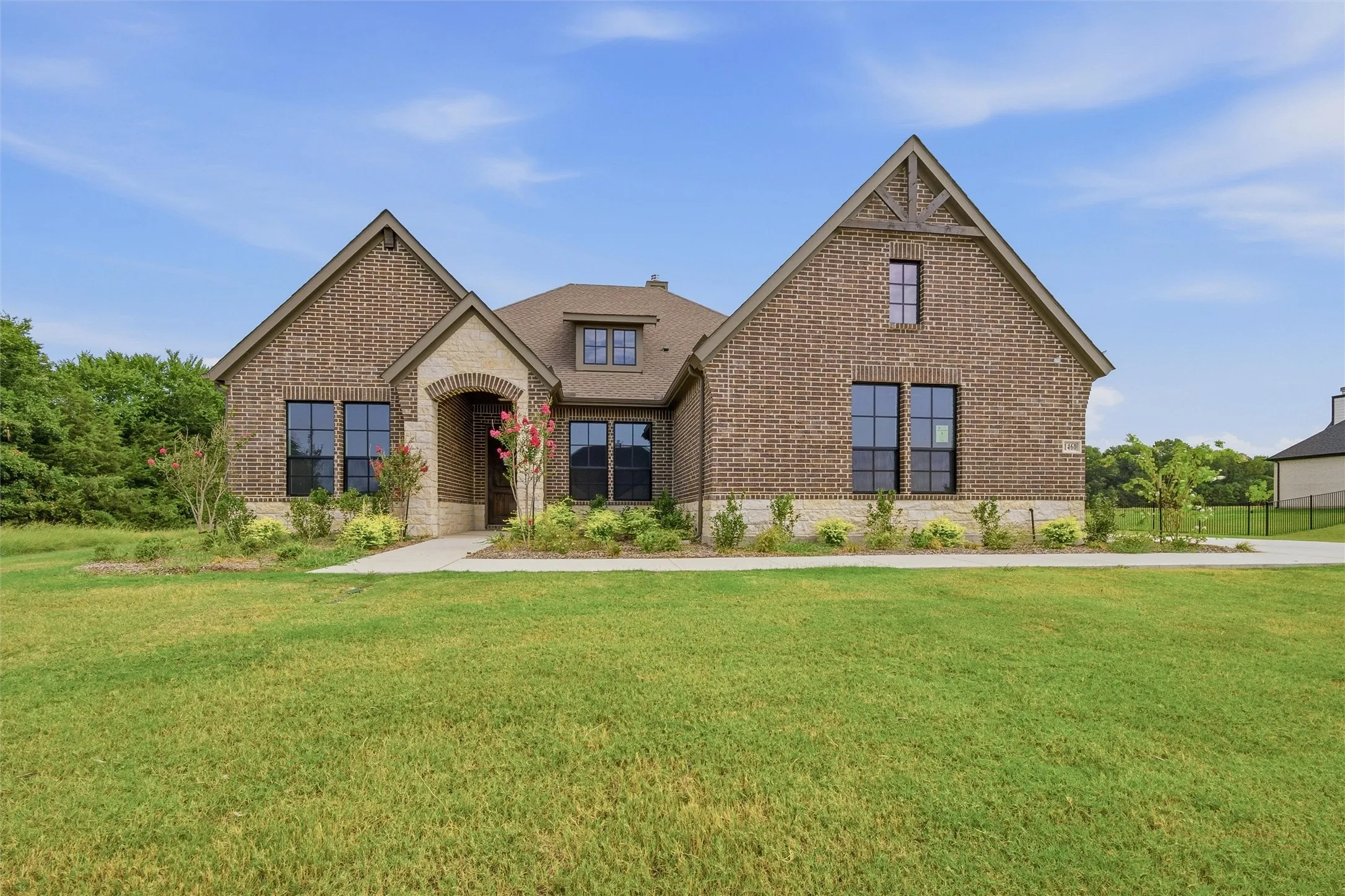 Brick and stone exterior with architectural gables, arched entry, and dark-framed windows