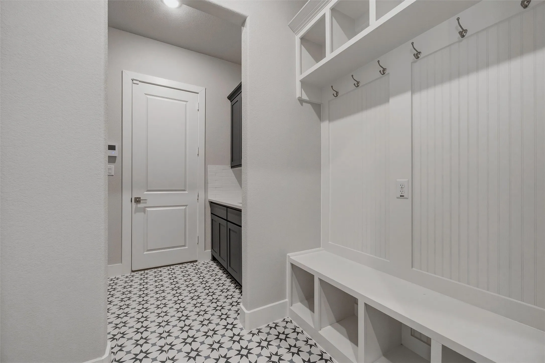 Built-in mudroom bench with cubby storage, upper shelving, and coat hooks