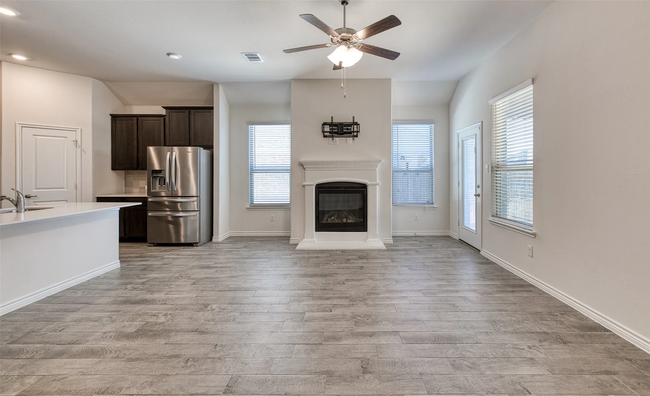 Unfurnished living room featuring a ceiling fan, a glass covered fireplace, and light wood-style flooring