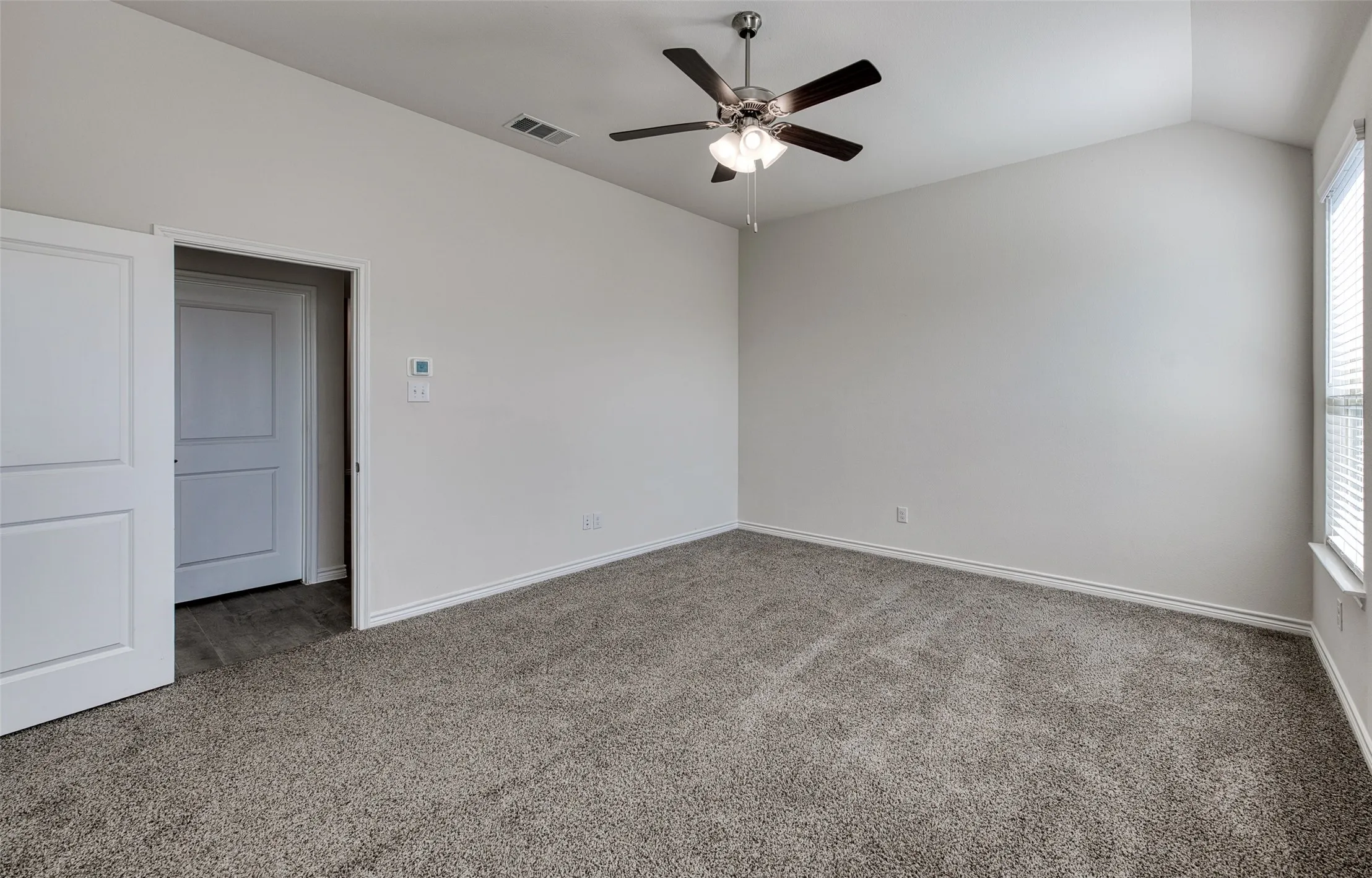 Spare room with carpet flooring, vaulted ceiling, ceiling fan, and plenty of natural light