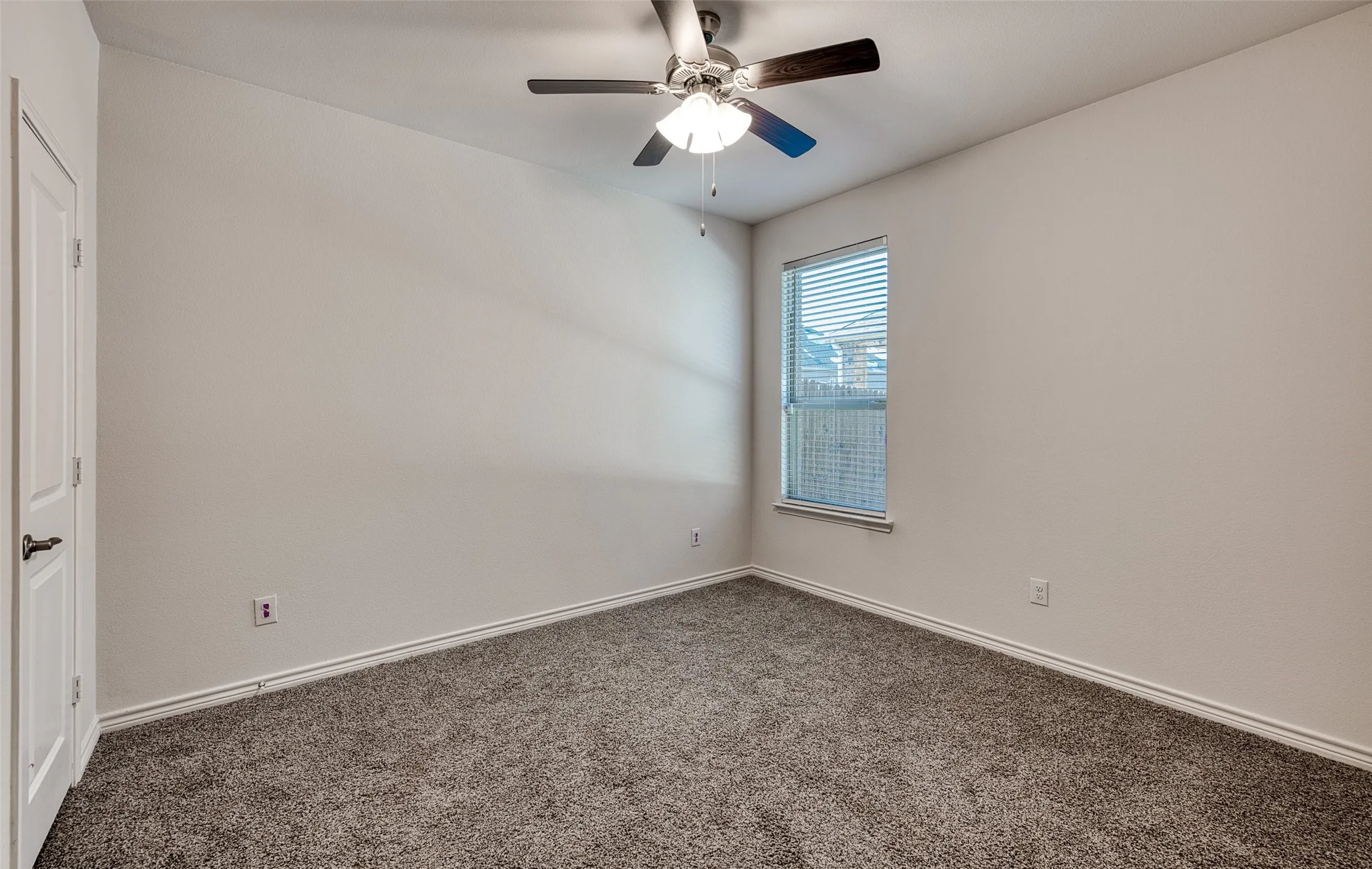 Carpeted empty room featuring baseboards and ceiling fan