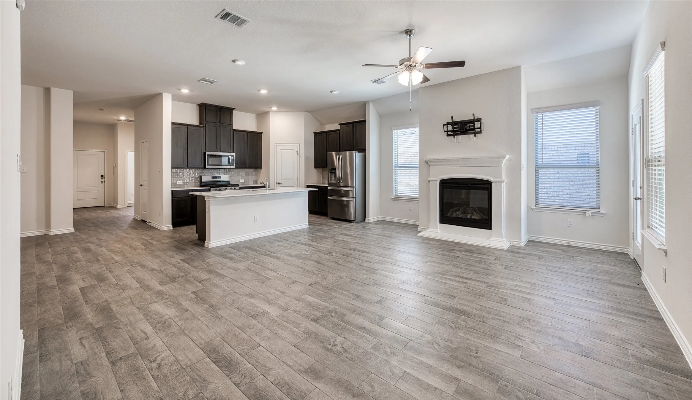 Kitchen with open floor plan, light countertops, stainless steel appliances, a ceiling fan, and a center island with sink