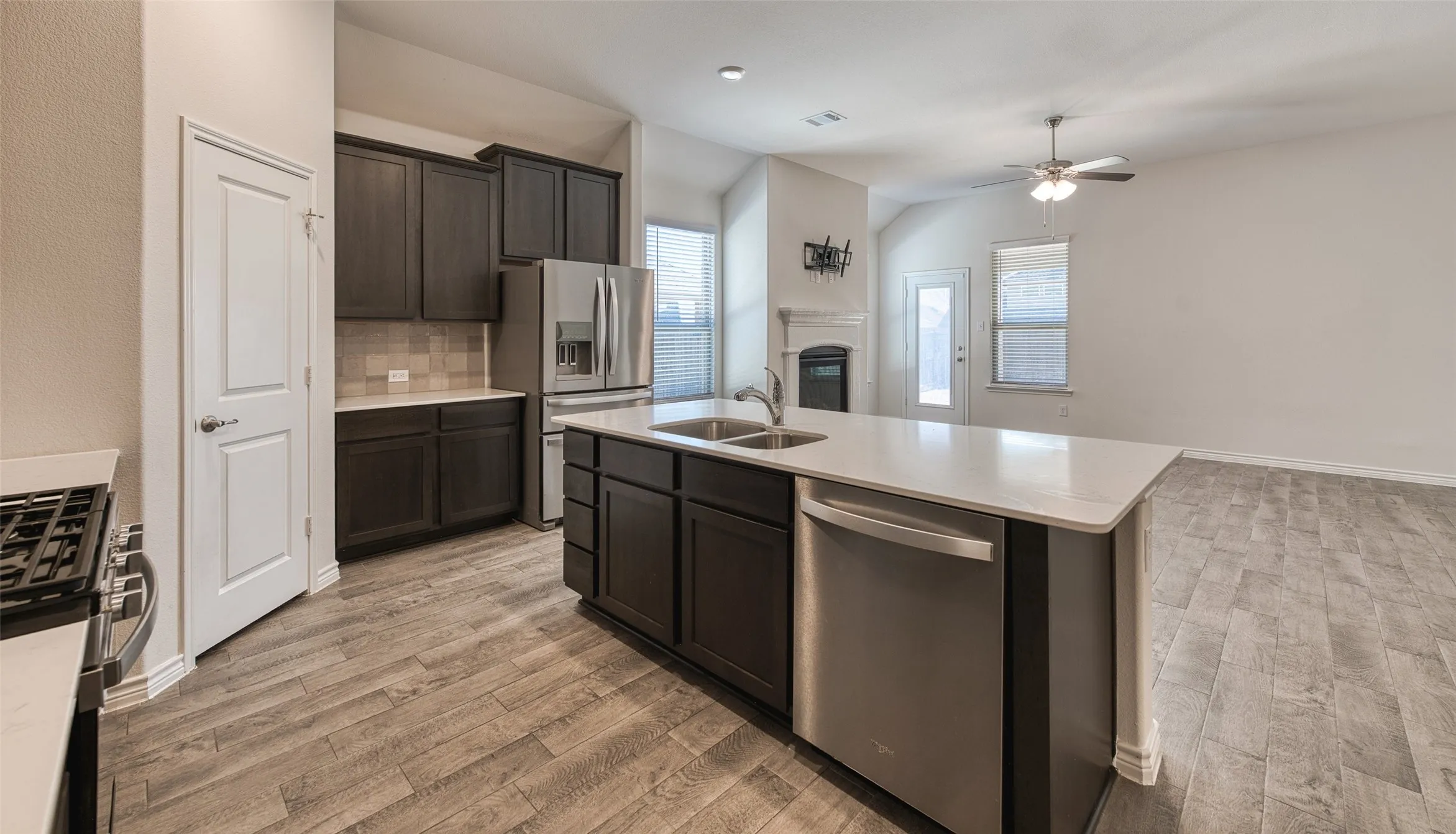 Kitchen featuring stainless steel appliances, open floor plan, decorative backsplash, an island with sink, and ceiling fan