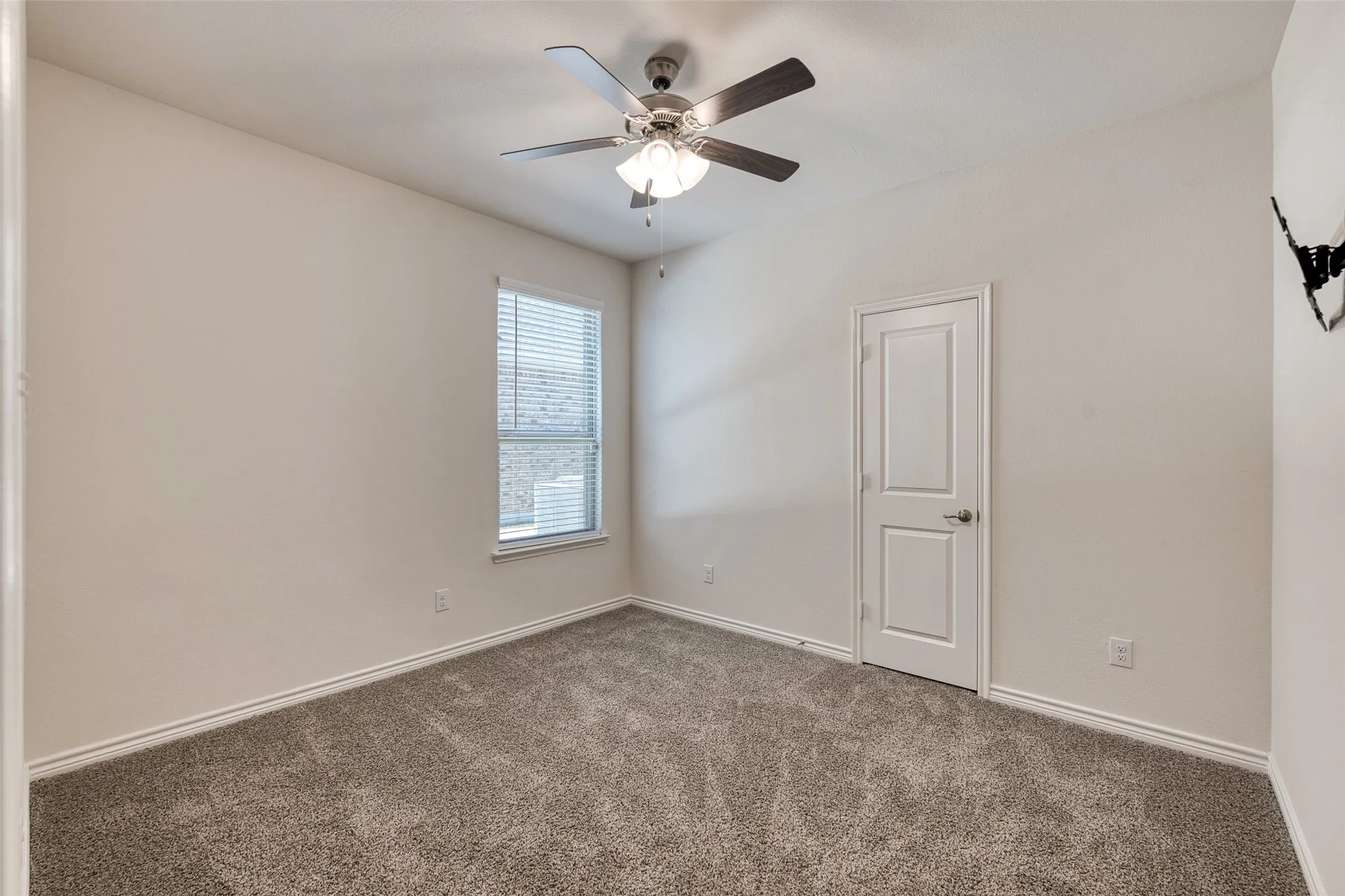 Carpeted empty room with baseboards and a ceiling fan