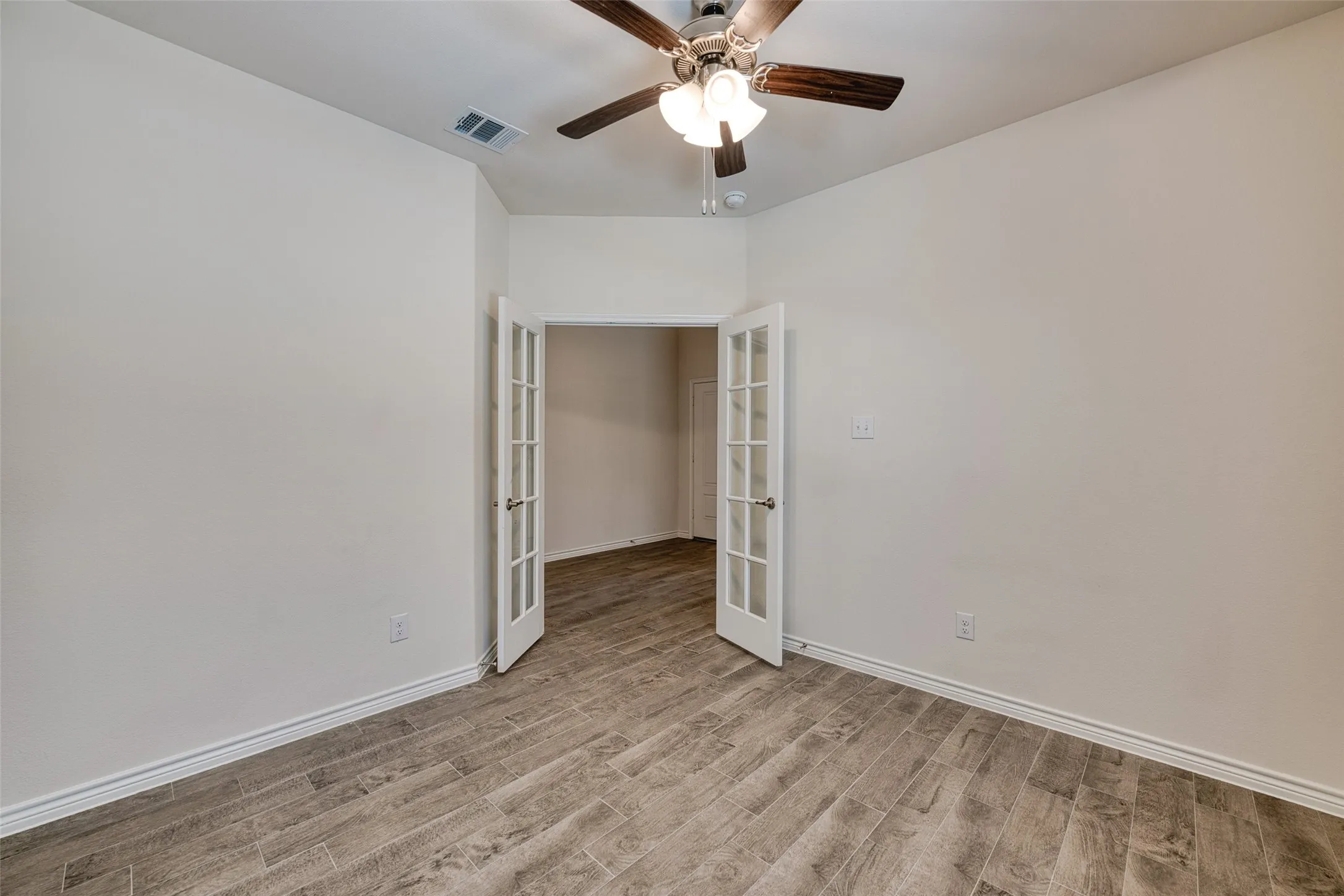 Unfurnished bedroom featuring french doors, light wood-type flooring, and a ceiling fan