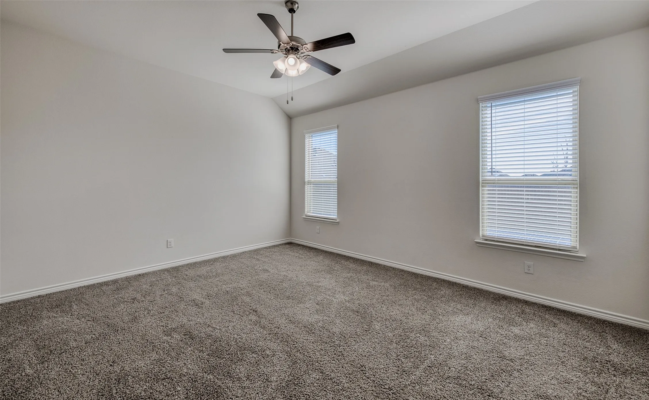 Empty room featuring carpet, lofted ceiling, and ceiling fan