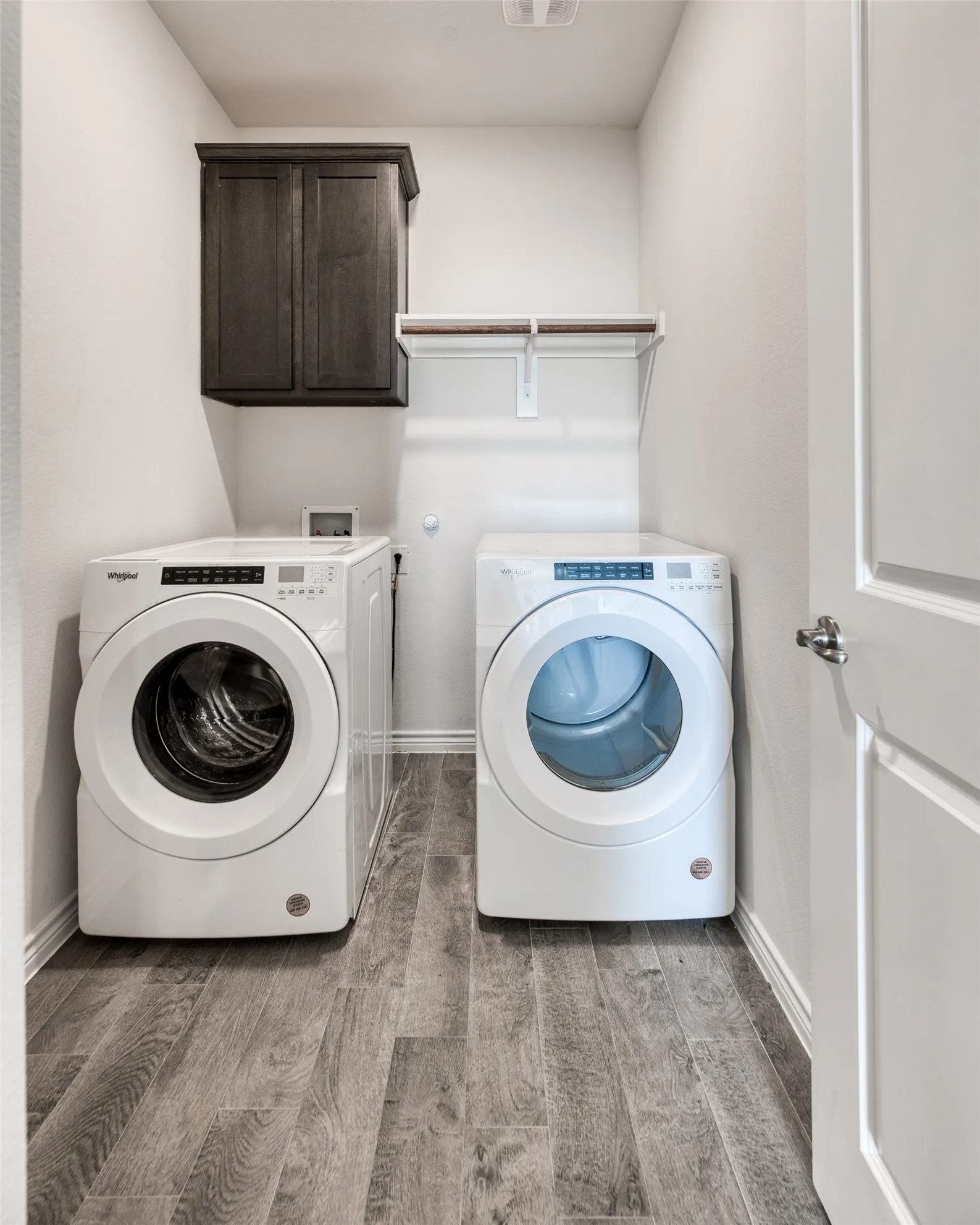 Laundry area featuring light wood-type flooring, cabinet space, and washing machine and dryer