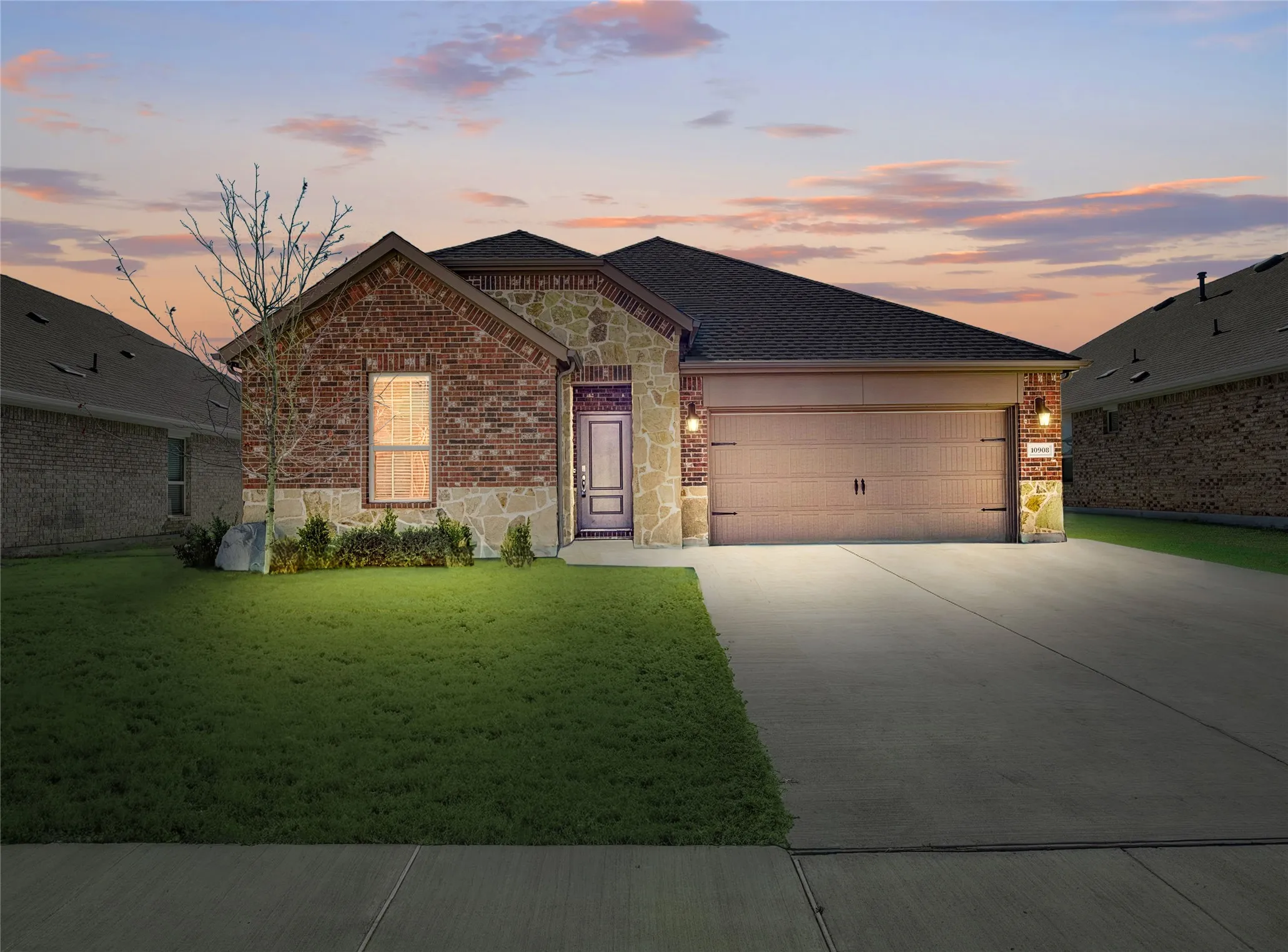 View of front of property featuring stone siding, brick siding, driveway, and an attached garage