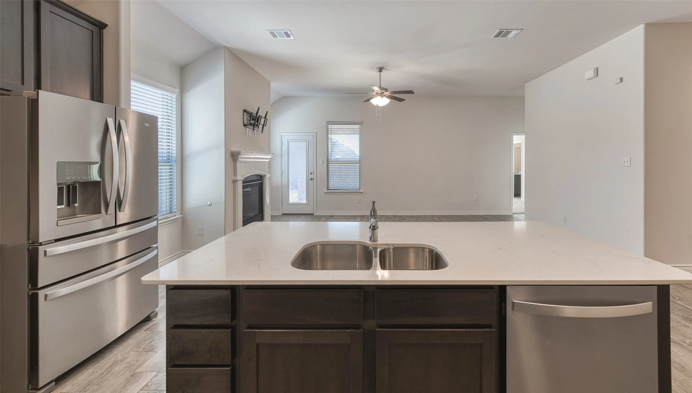 Kitchen with dark wood finish cabinets, stainless steel appliances, a kitchen island with sink, and open floor plan