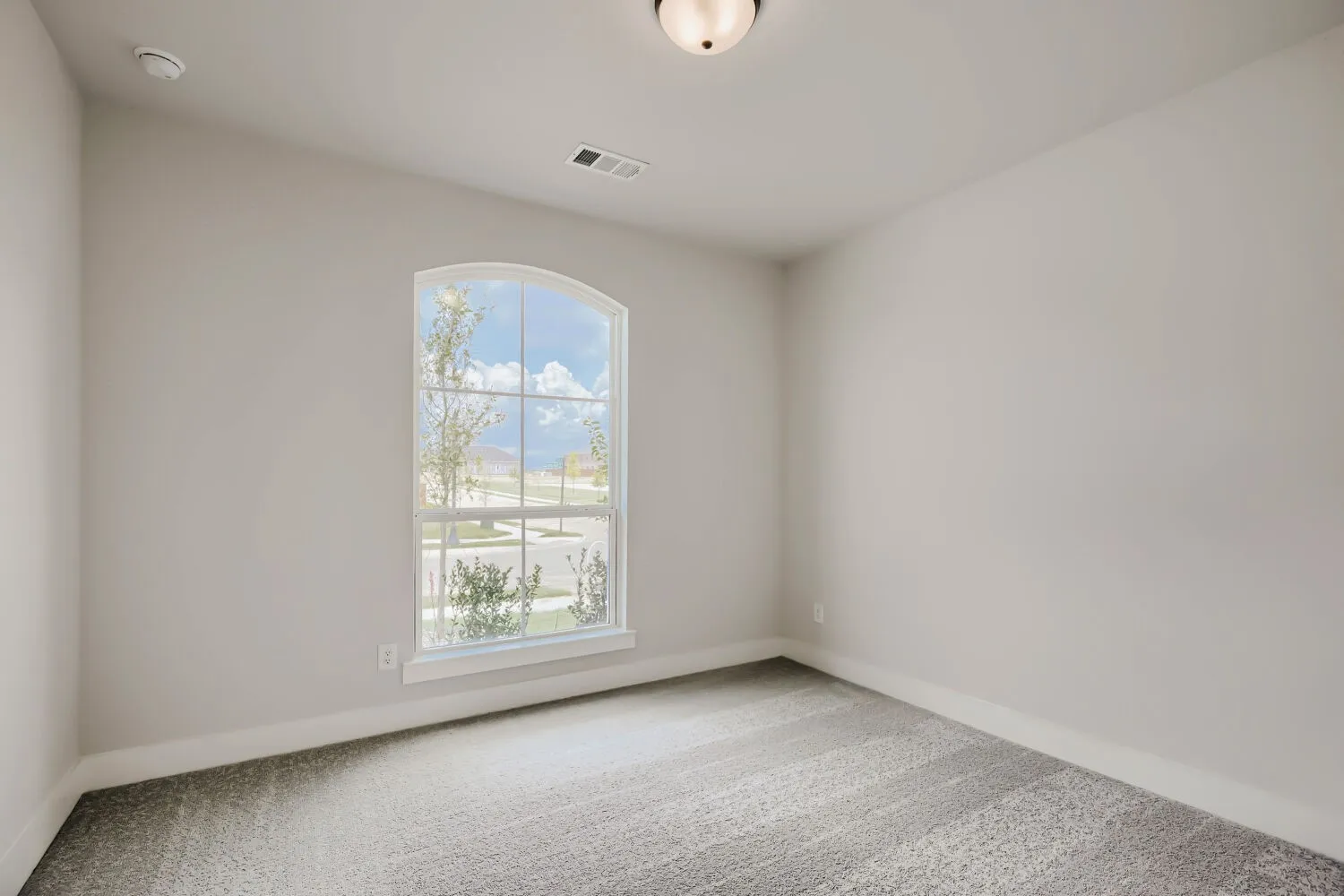 Room featuring a large arched window, light gray walls, gray carpet, white baseboards, and a semi-flush ceiling light fixture