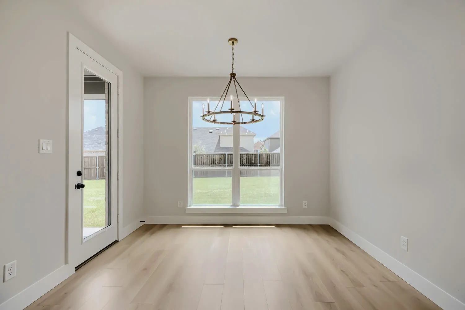 Dining area featuring a contemporary chandelier, wood-finish flooring, and a glass-paned door to the exterior