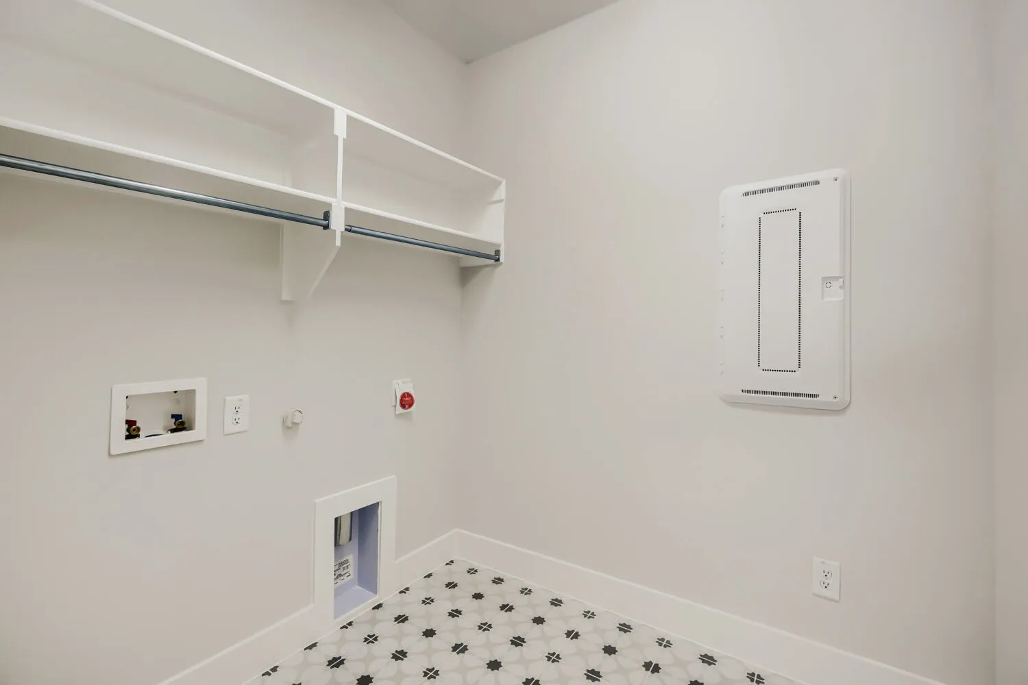 Utility room with patterned floor tile, overhead shelving, and a hanging rod