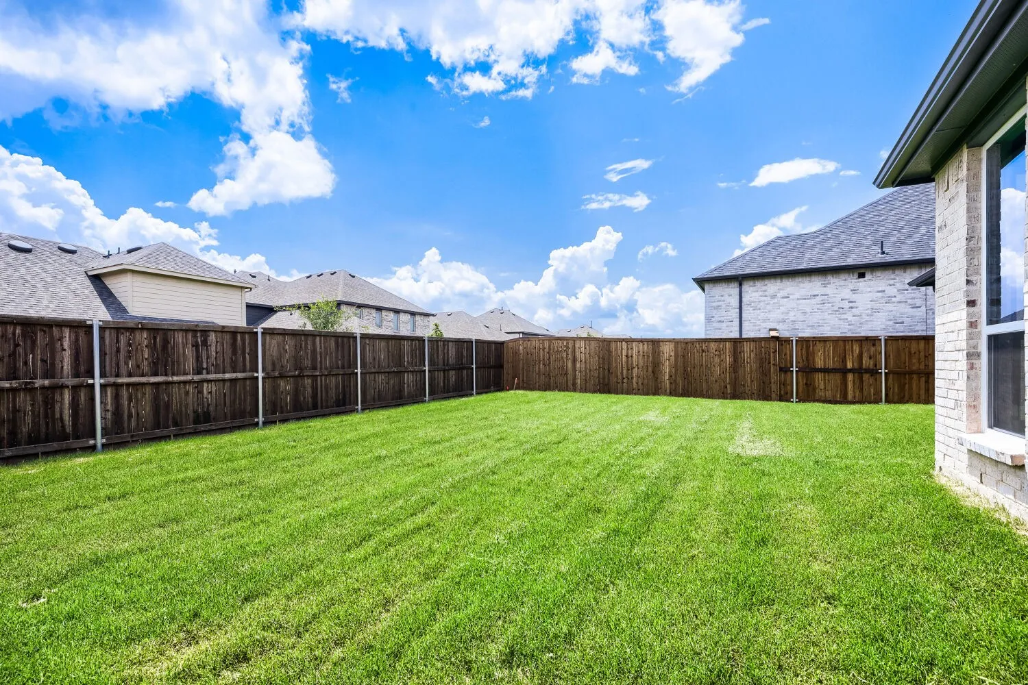 Expansive green lawn with a full privacy fence