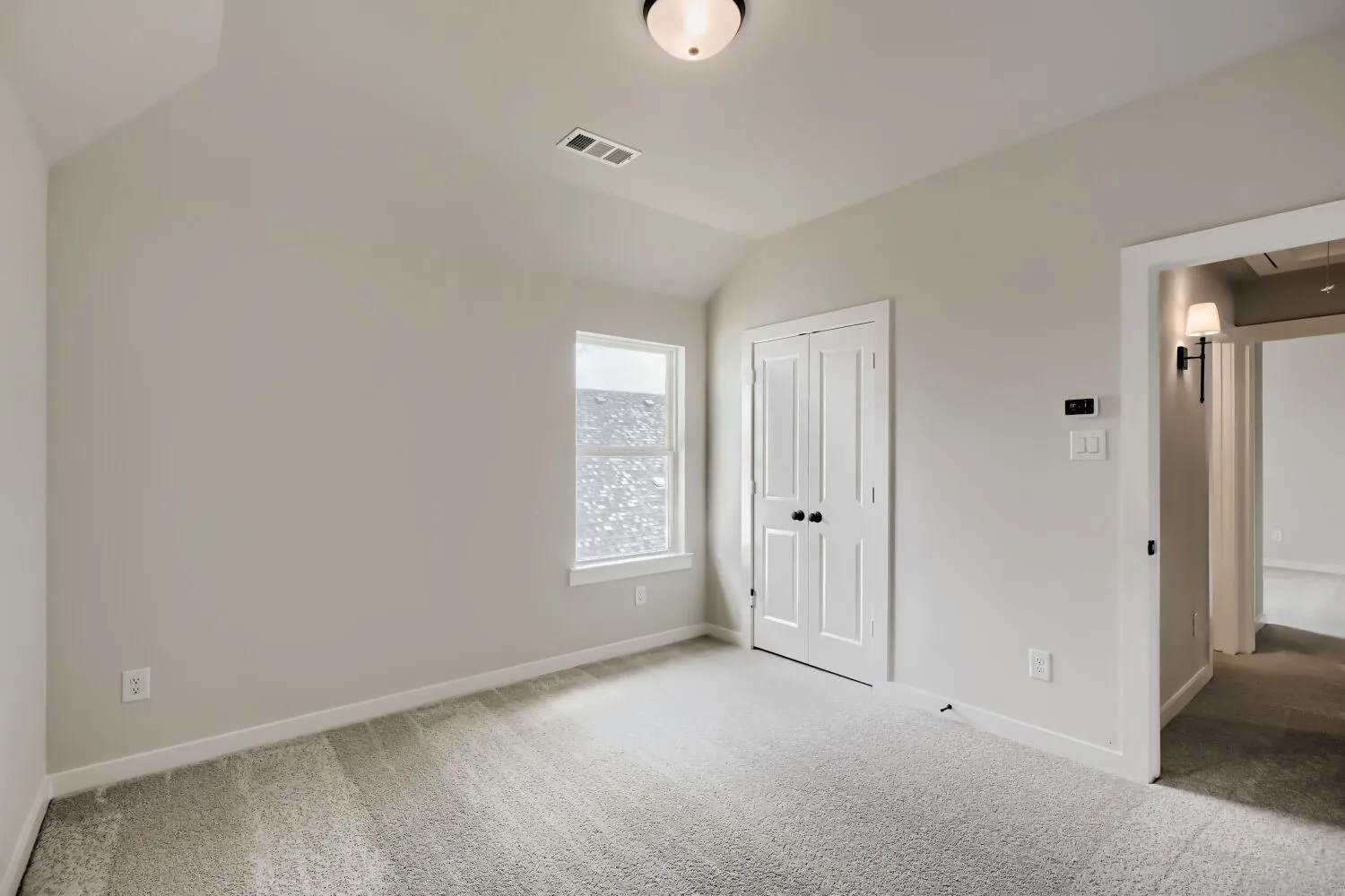 Room featuring light gray carpeting, vaulted ceiling, and a prominent window