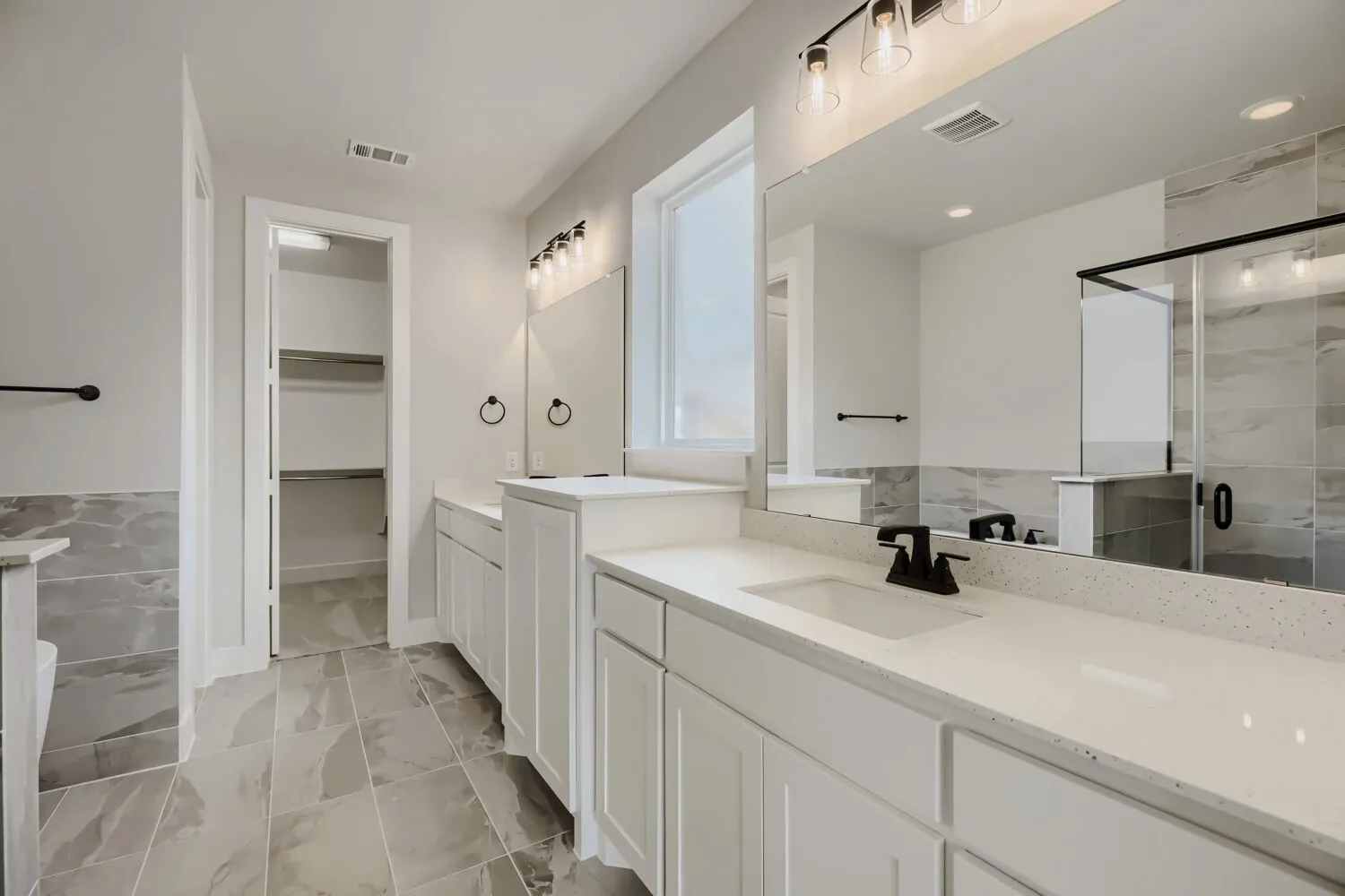 Dual vanities with white cabinetry and light-toned countertops, featuring matte black fixtures