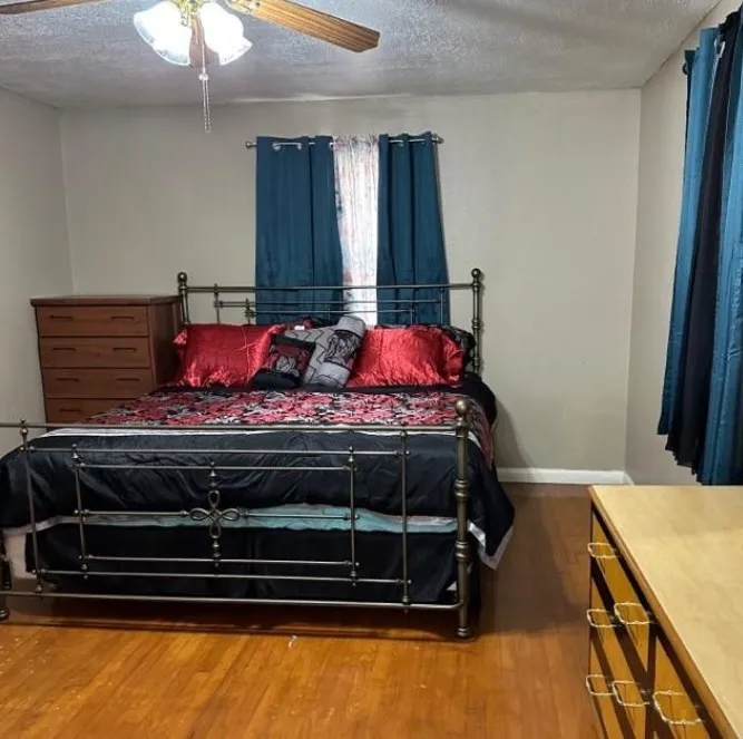 Bedroom with dark wood-style floors, a textured ceiling, and a ceiling fan