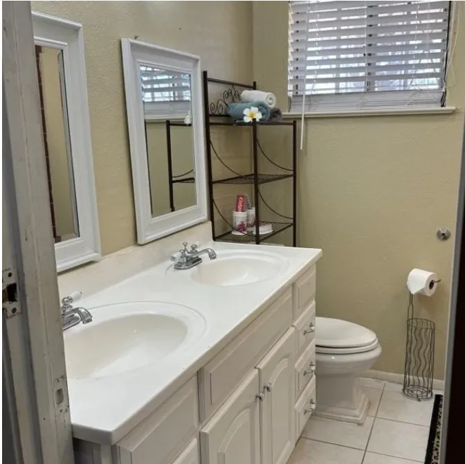 Bathroom featuring double vanity, light tile patterned flooring, and a textured wall
