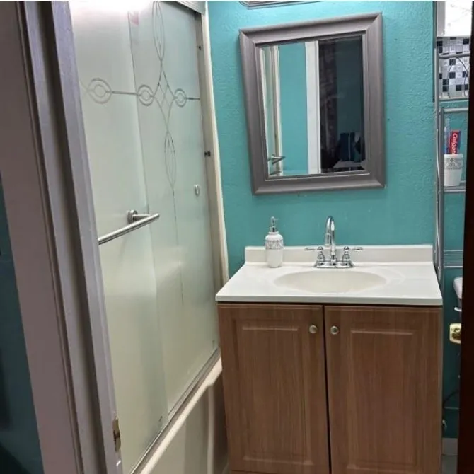 Full bathroom with vanity, a textured wall, and combined bath / shower with glass door