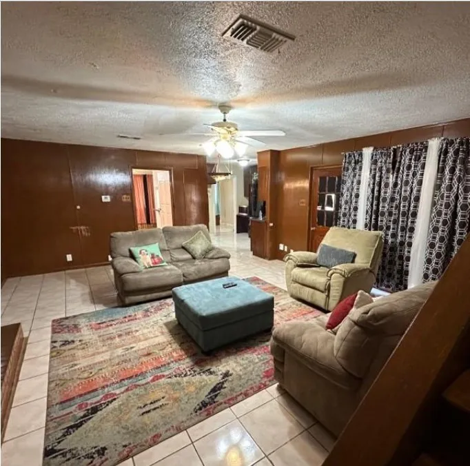 Living room with light tile patterned floors, a textured ceiling, and ceiling fan