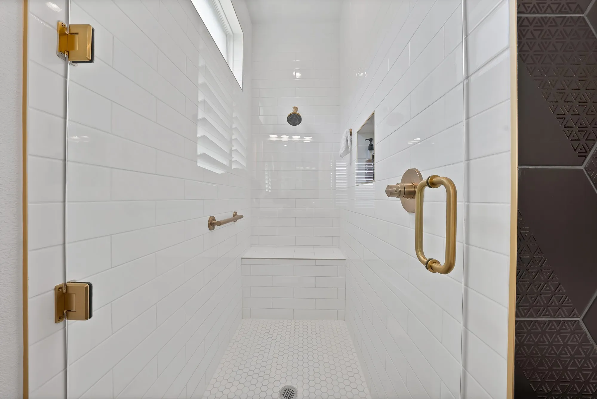 Spacious shower enclosure featuring clear glass panels with gold-tone hardware