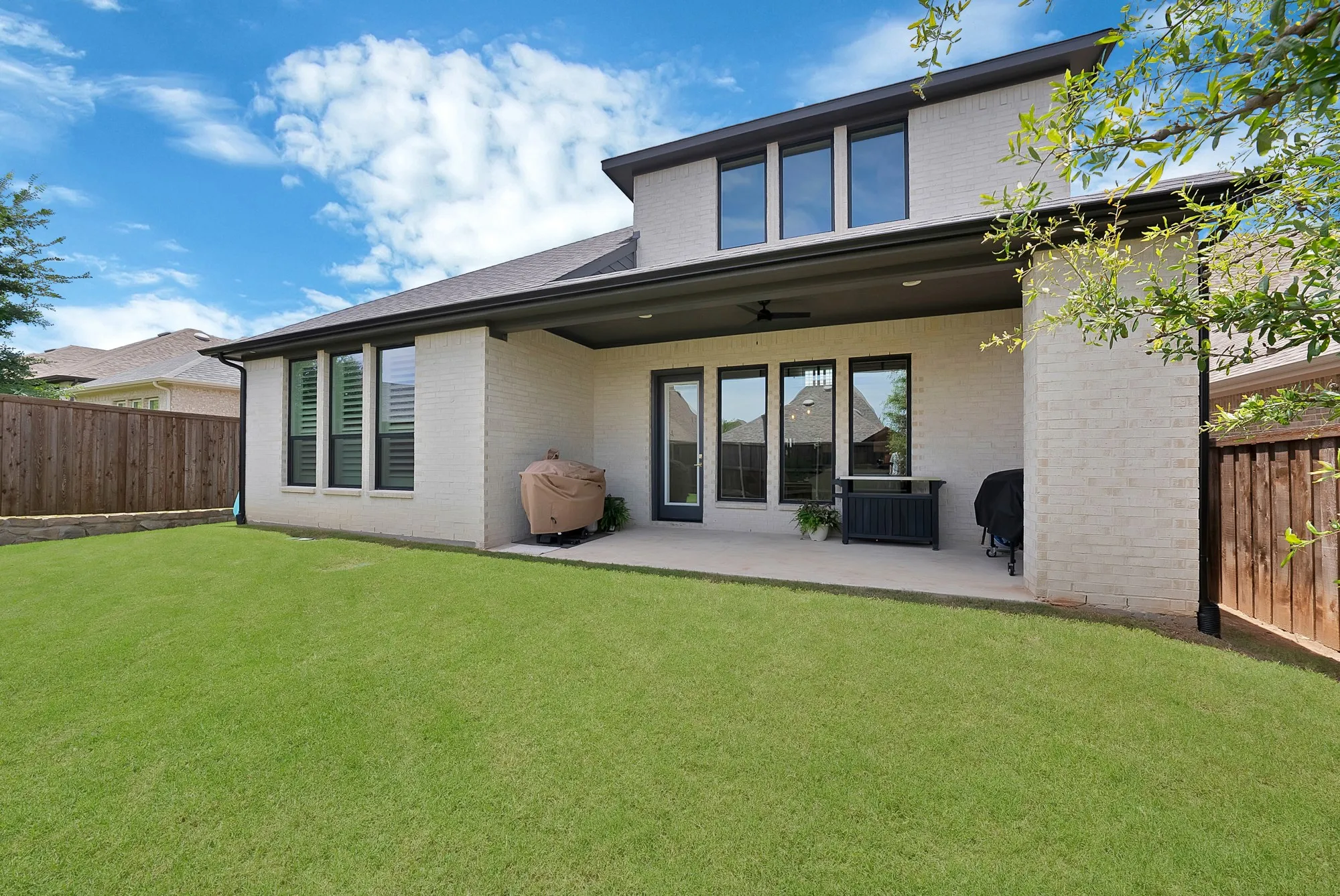 Expansive backyard featuring a manicured lawn, a large concrete patio, and a covered outdoor living area