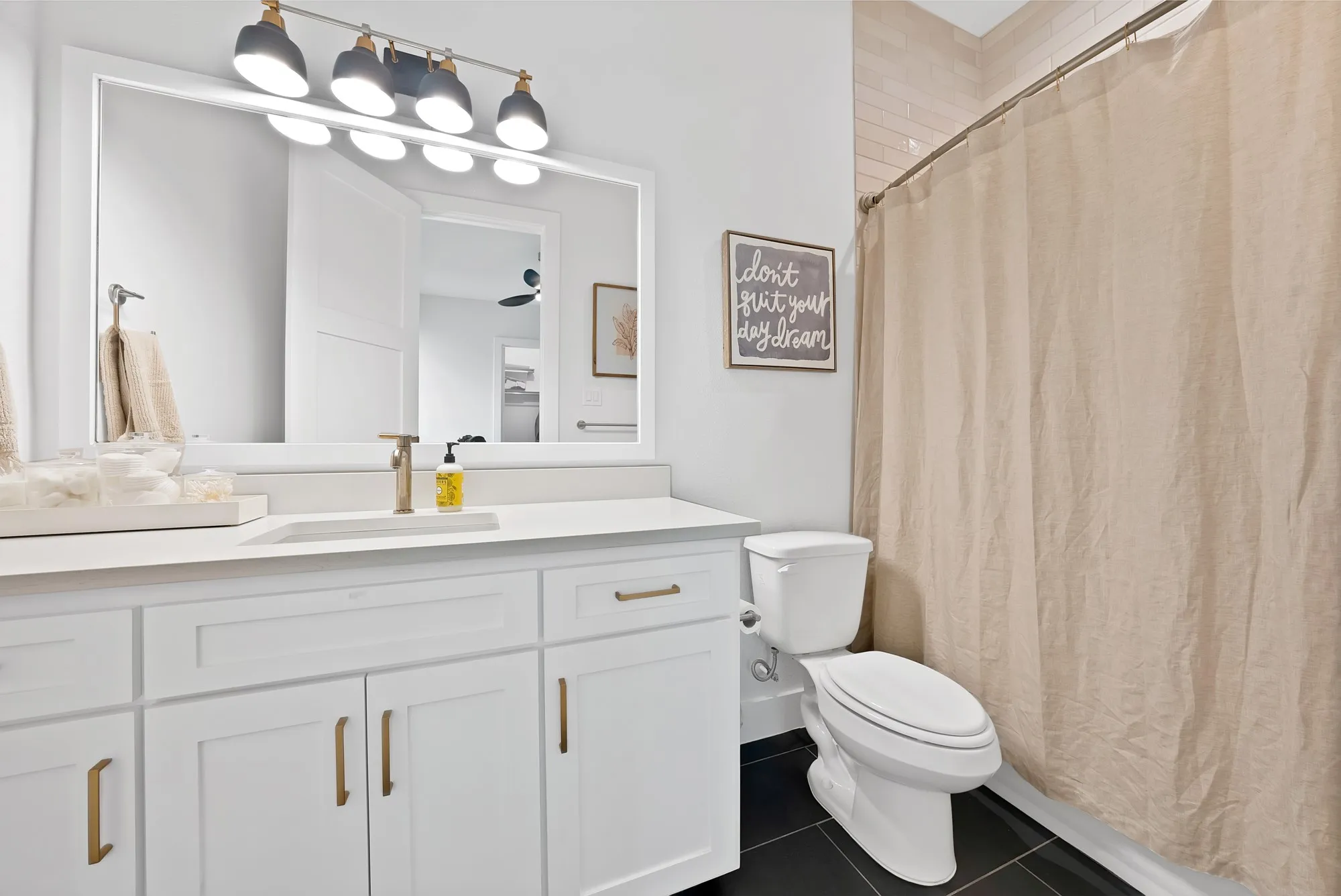 Bathroom featuring a white vanity with gold-tone hardware, a rectangular undermount sink, and a single-handle faucet