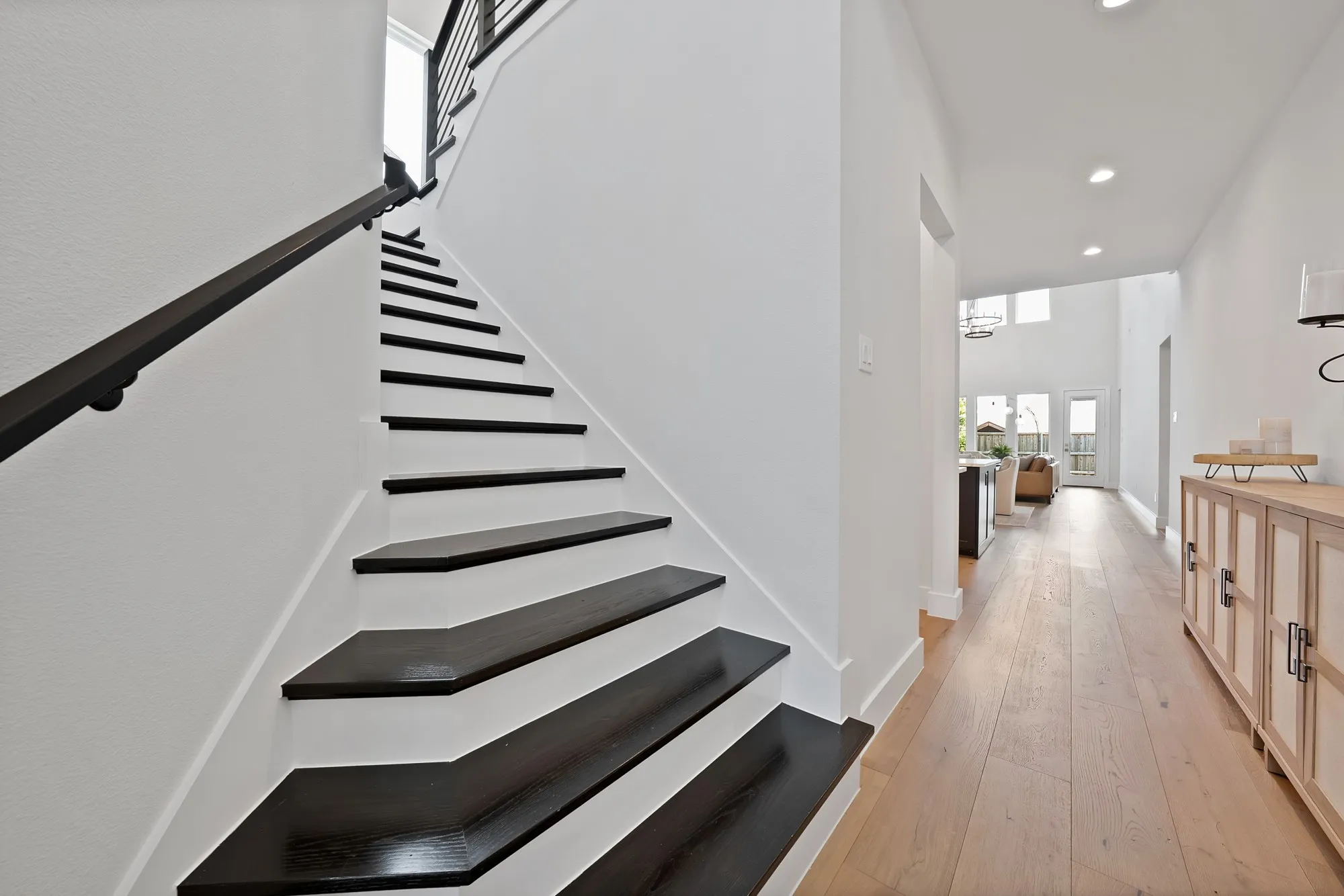 Staircase featuring dark wood-finish treads, white risers, and a contemporary black metal railing
