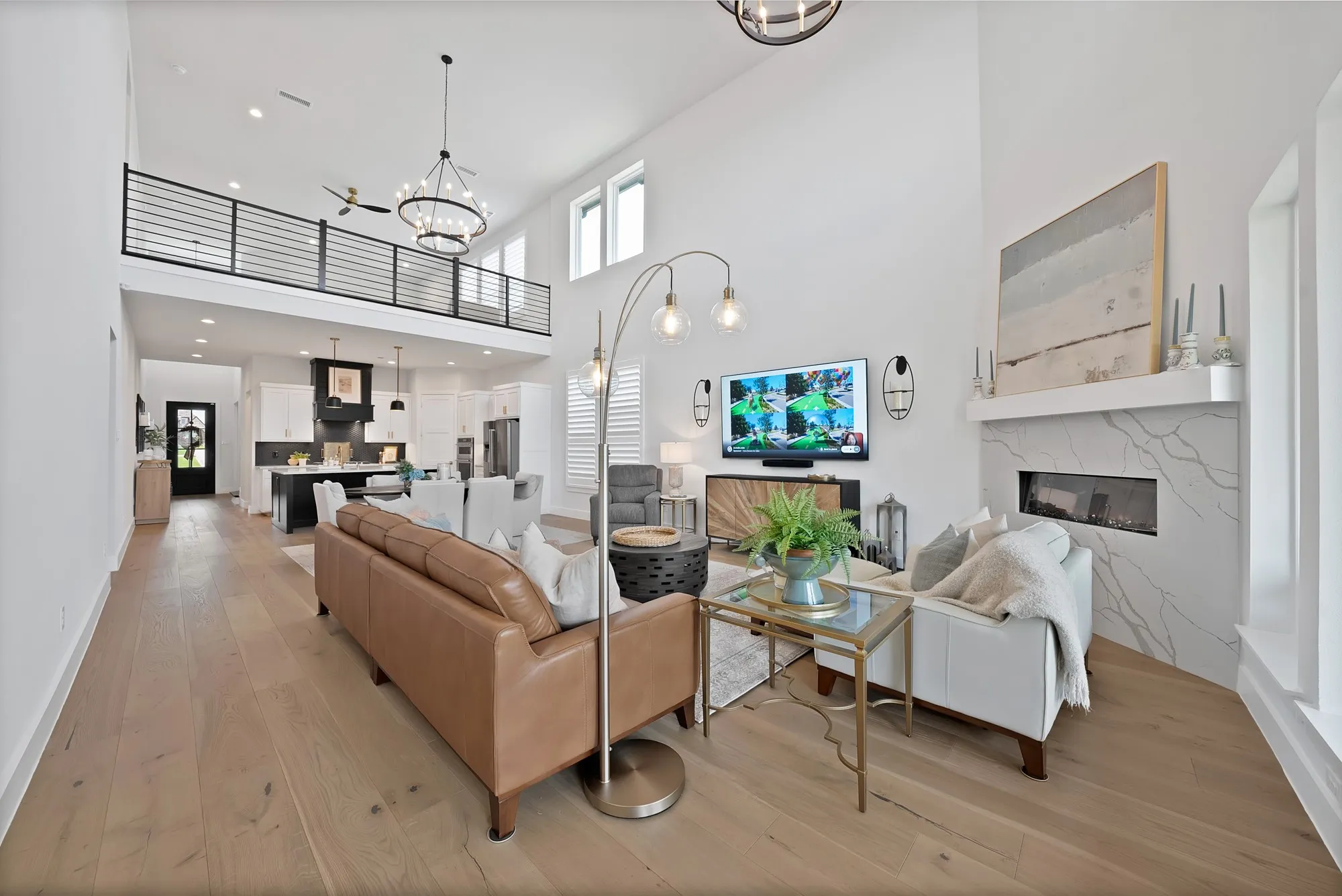 Great room featuring high ceilings, wood-finish flooring, and a linear fireplace with a stone surround