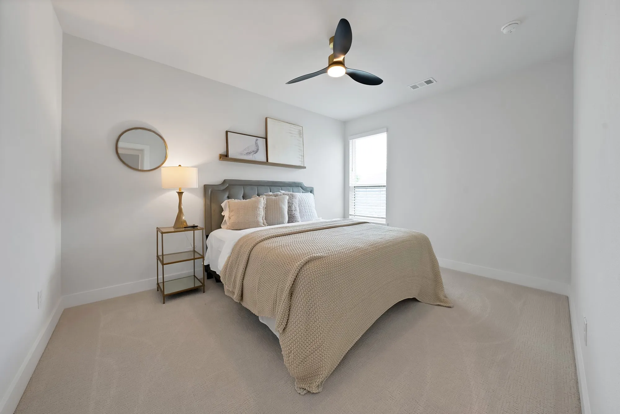 Neutral-toned carpeted room featuring a ceiling fan with integrated lighting, a single window with blinds, and white baseboards