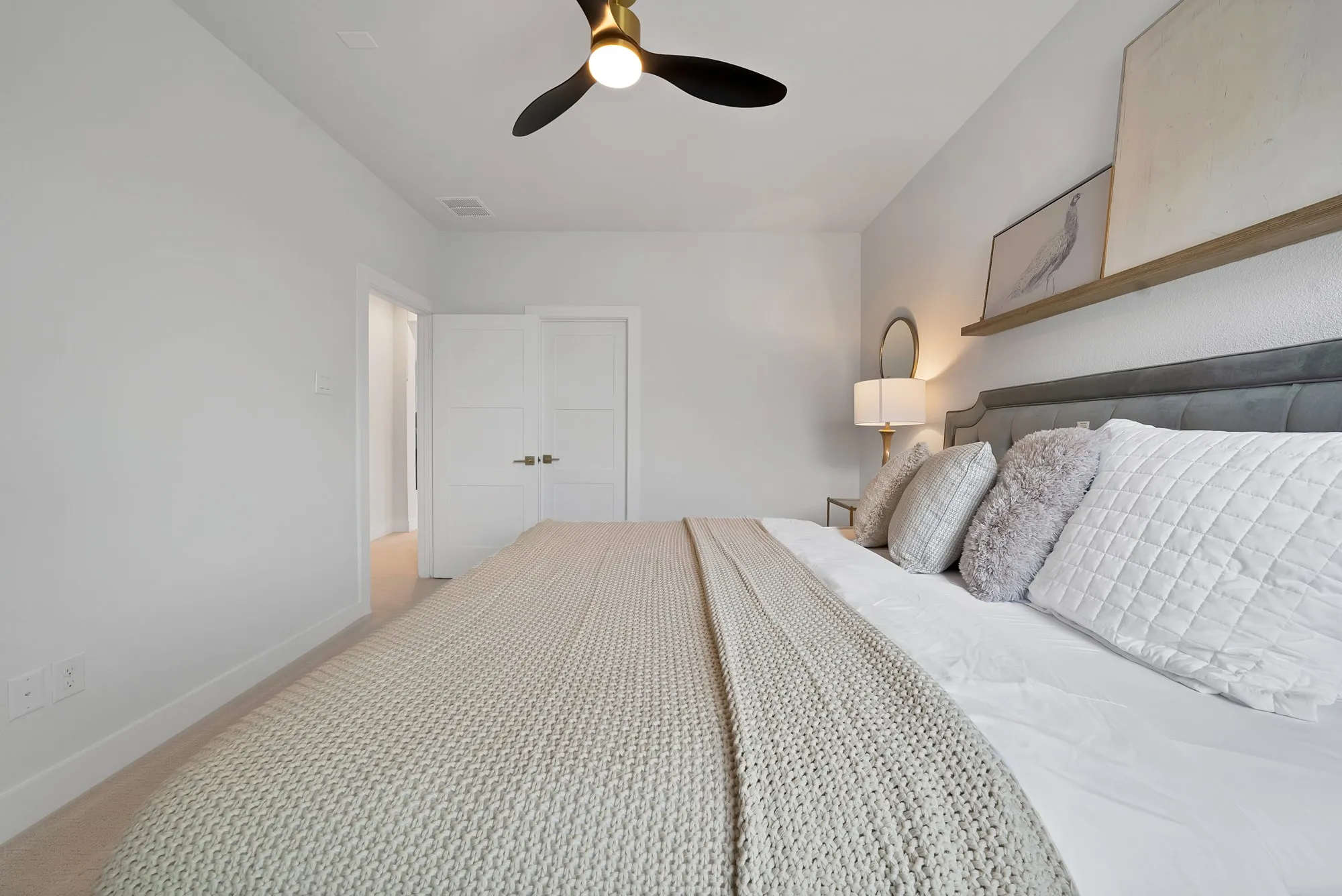 Gold-finish ceiling fan with black blades, light gray carpet flooring, white walls, and white trim