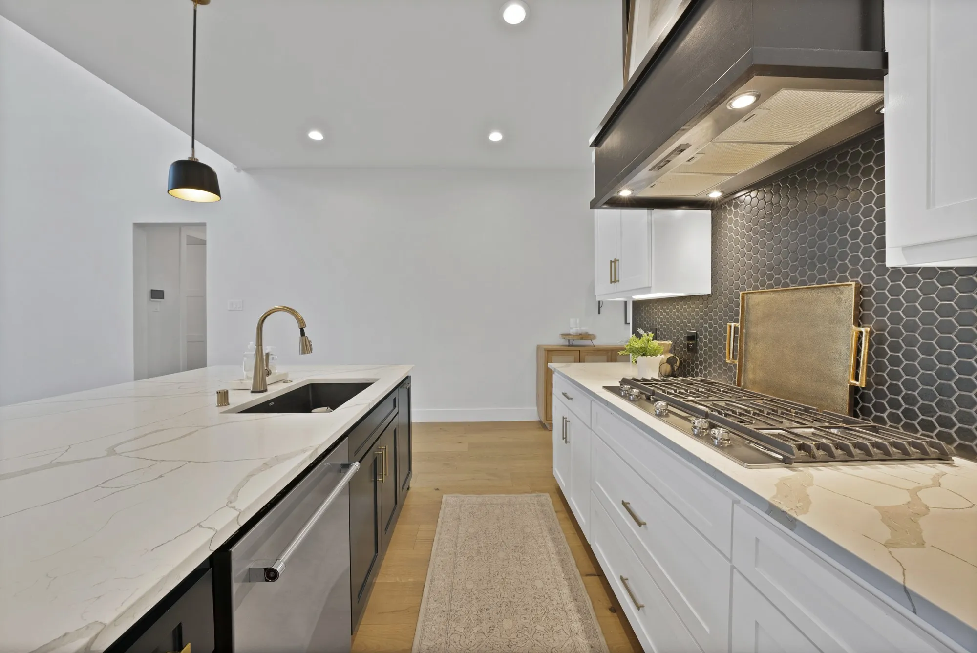 Modern kitchen featuring white cabinetry, a dark hexagonal tile backsplash, light wood-finish flooring, and light countertops