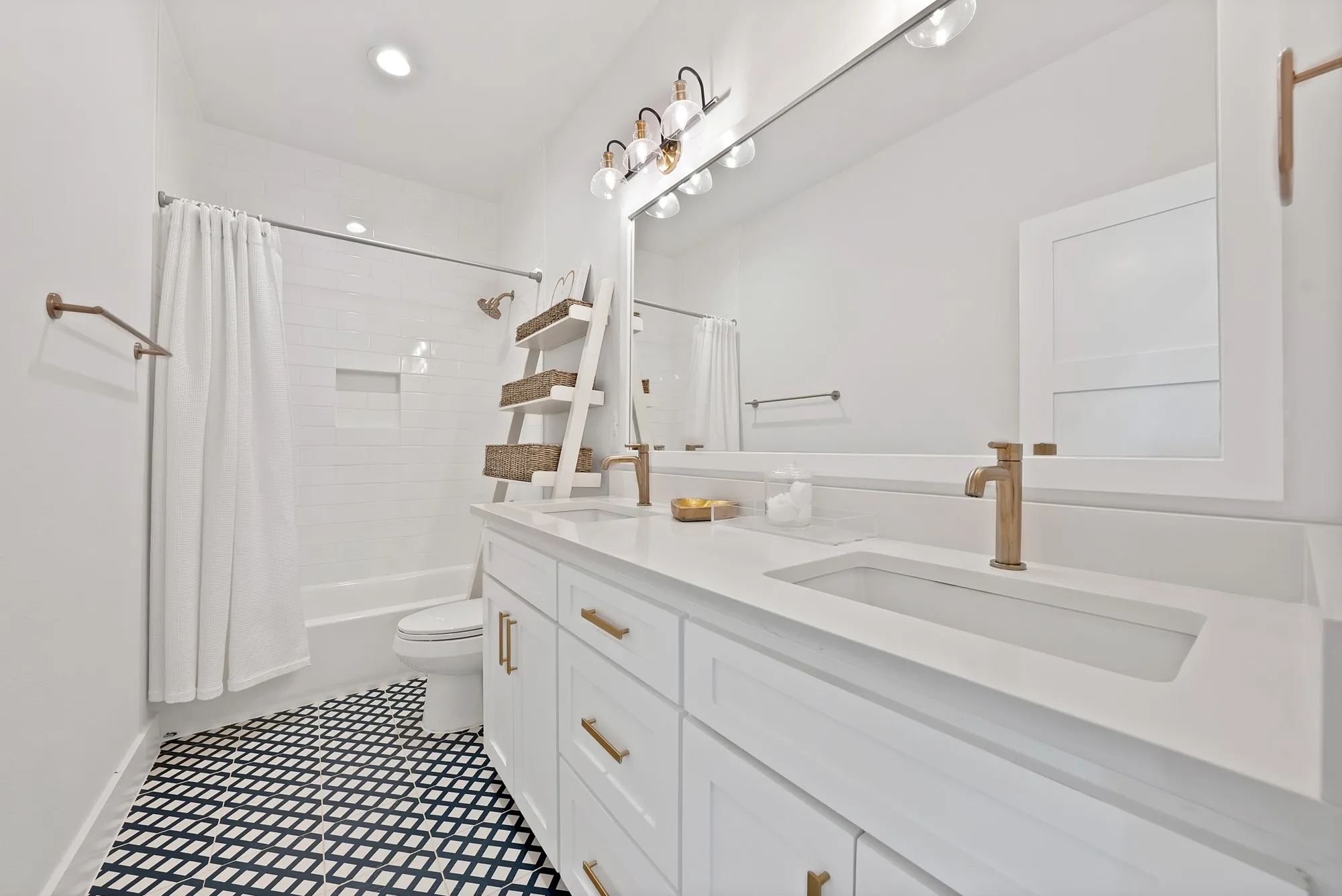 Modern bathroom featuring a dual vanity with integrated sinks, white cabinetry, and brushed gold hardware