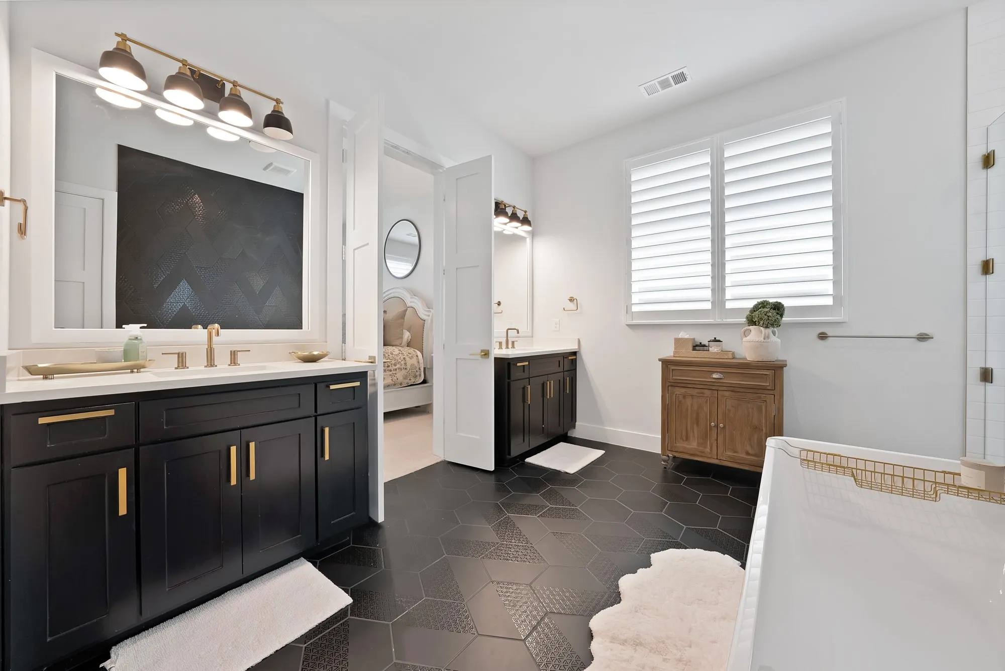 Bathroom featuring dual black vanities with gold hardware, white countertops, and a full-width mirror