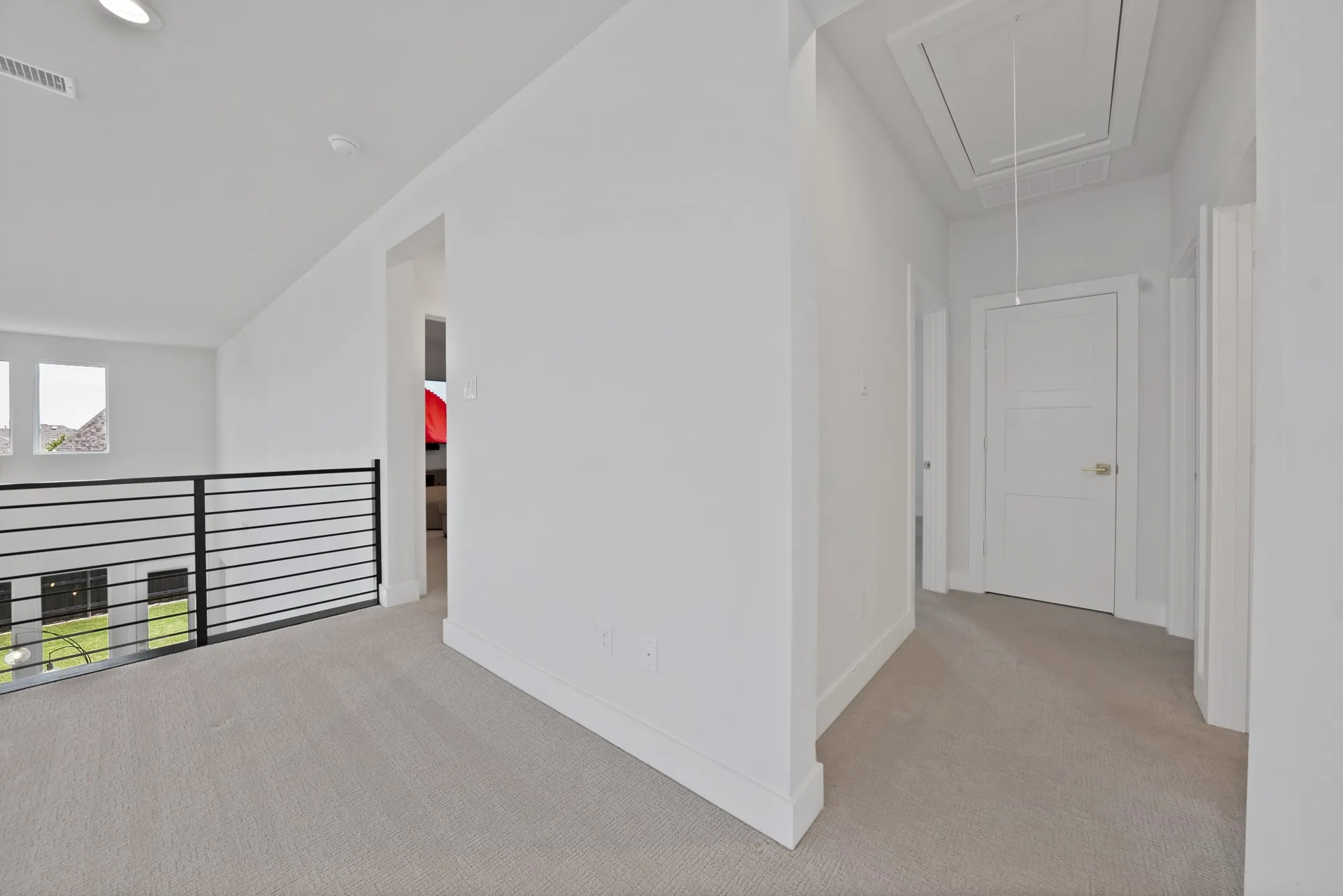 Second-story landing featuring plush carpeting, contemporary black metal railing, recessed lighting, and crisp white trim